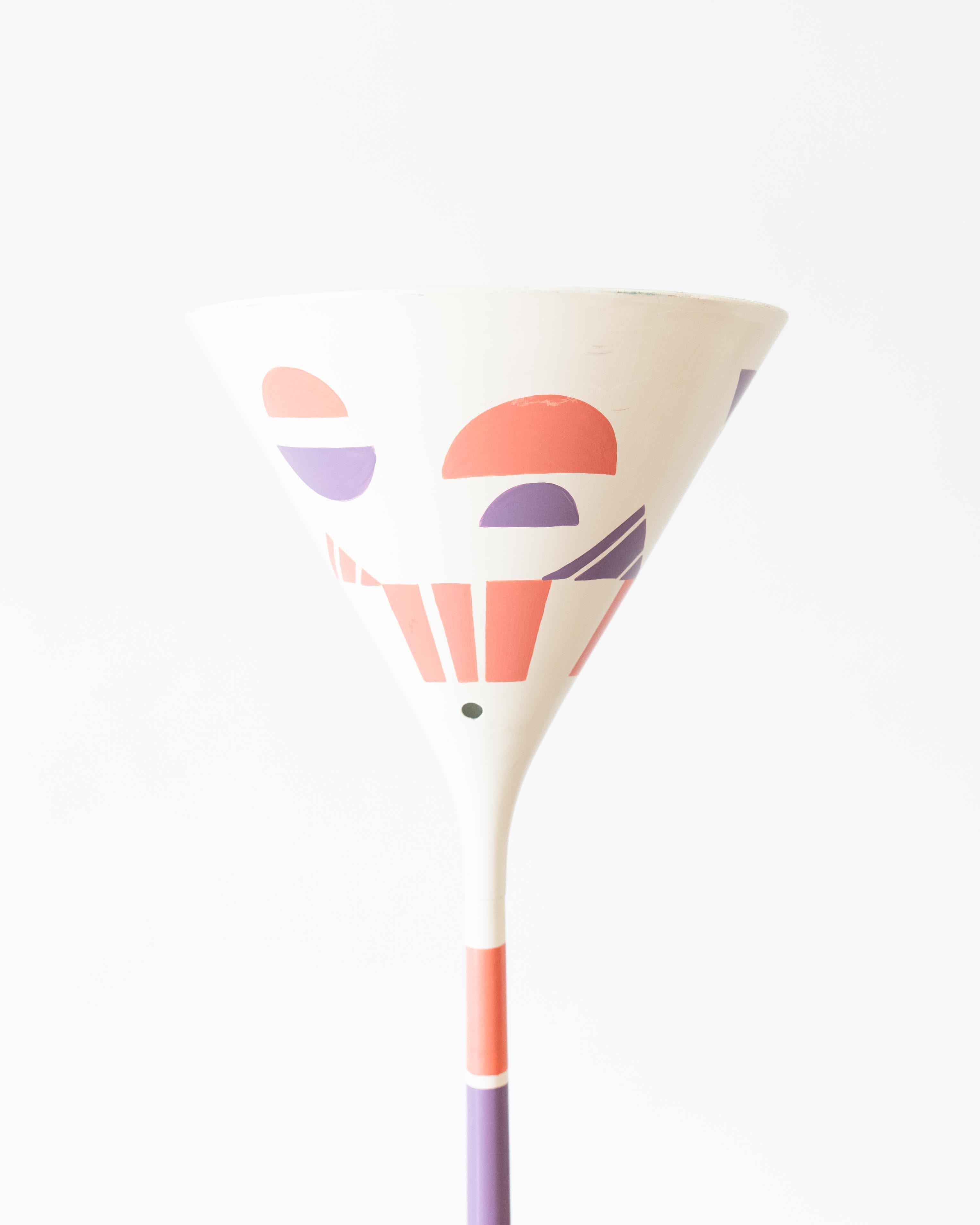 Mid-Century Modern painted torchiere floor lamp finished in metal, featuring a cone shade, finished in a creamy white base color with purple and deep pink geometric abstract motifs throughout.