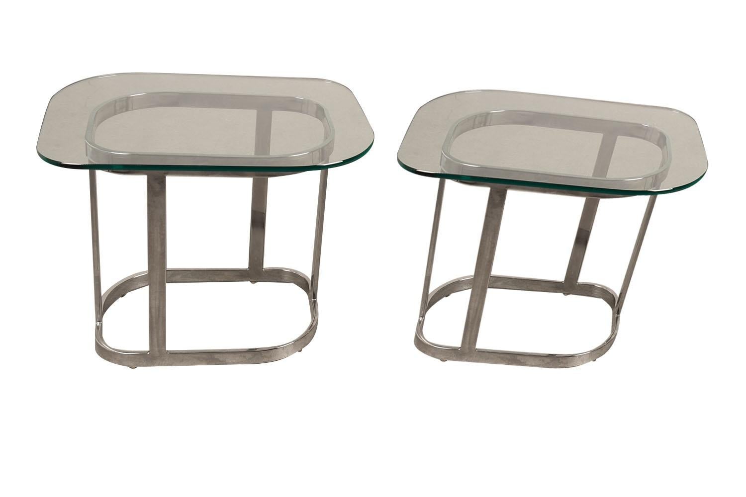 Une extraordinaire paire de tables d'appoint en verre du milieu du siècle au design moderniste élégant et luxuriant. Chacune présente un verre original de 3/8″ d'épaisseur reposant sur une base chromée avec des barres plates chromées de 1/2″