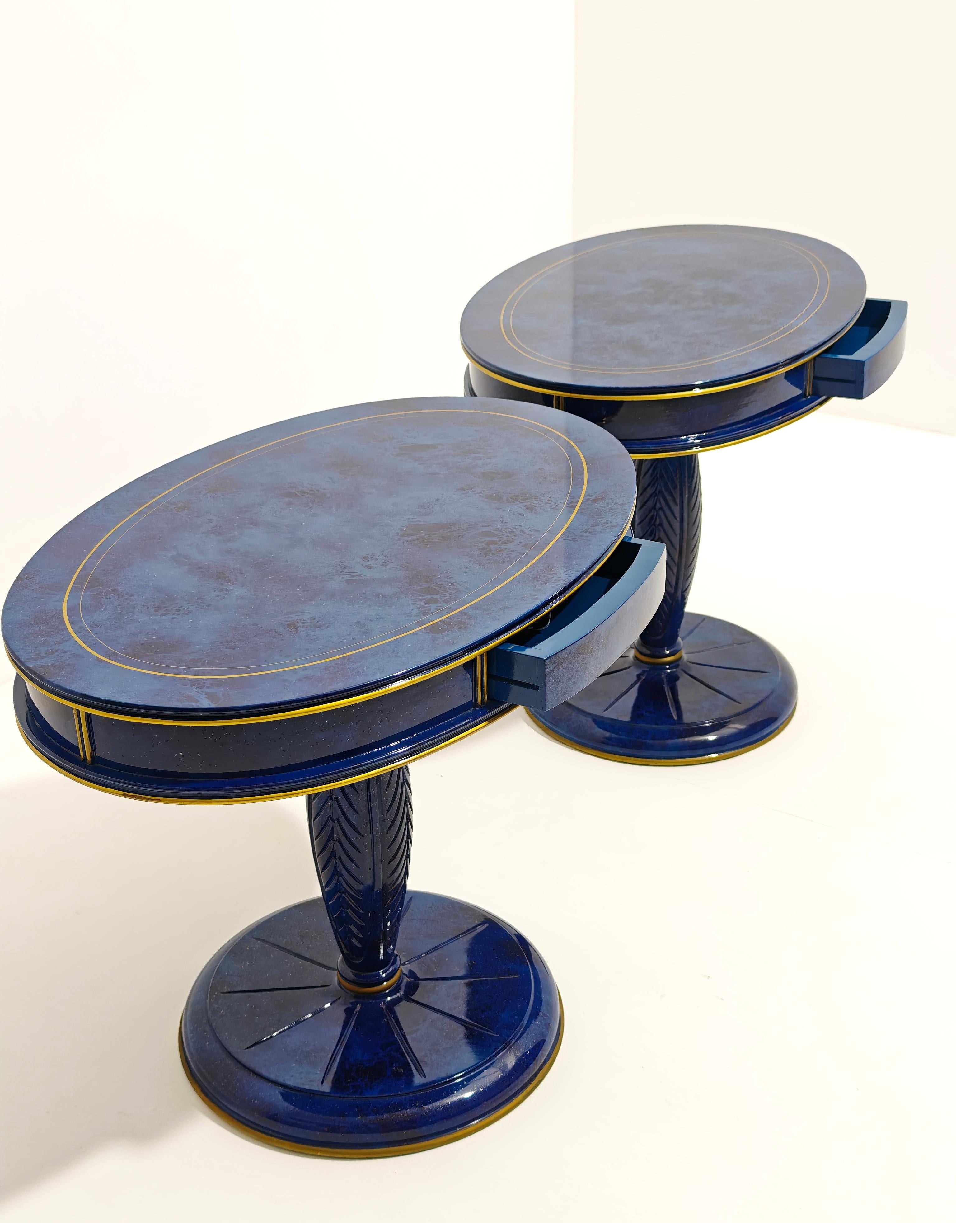 ANNIBALE COLOMBO. Made in Italy, ca. 1980
Pair of bedside tables with wooden frame and lapis lazuli-effect finish and gold highlights, oval top with small central drawer on the front, elliptical foot decorated with plant motifs, circular base. They
