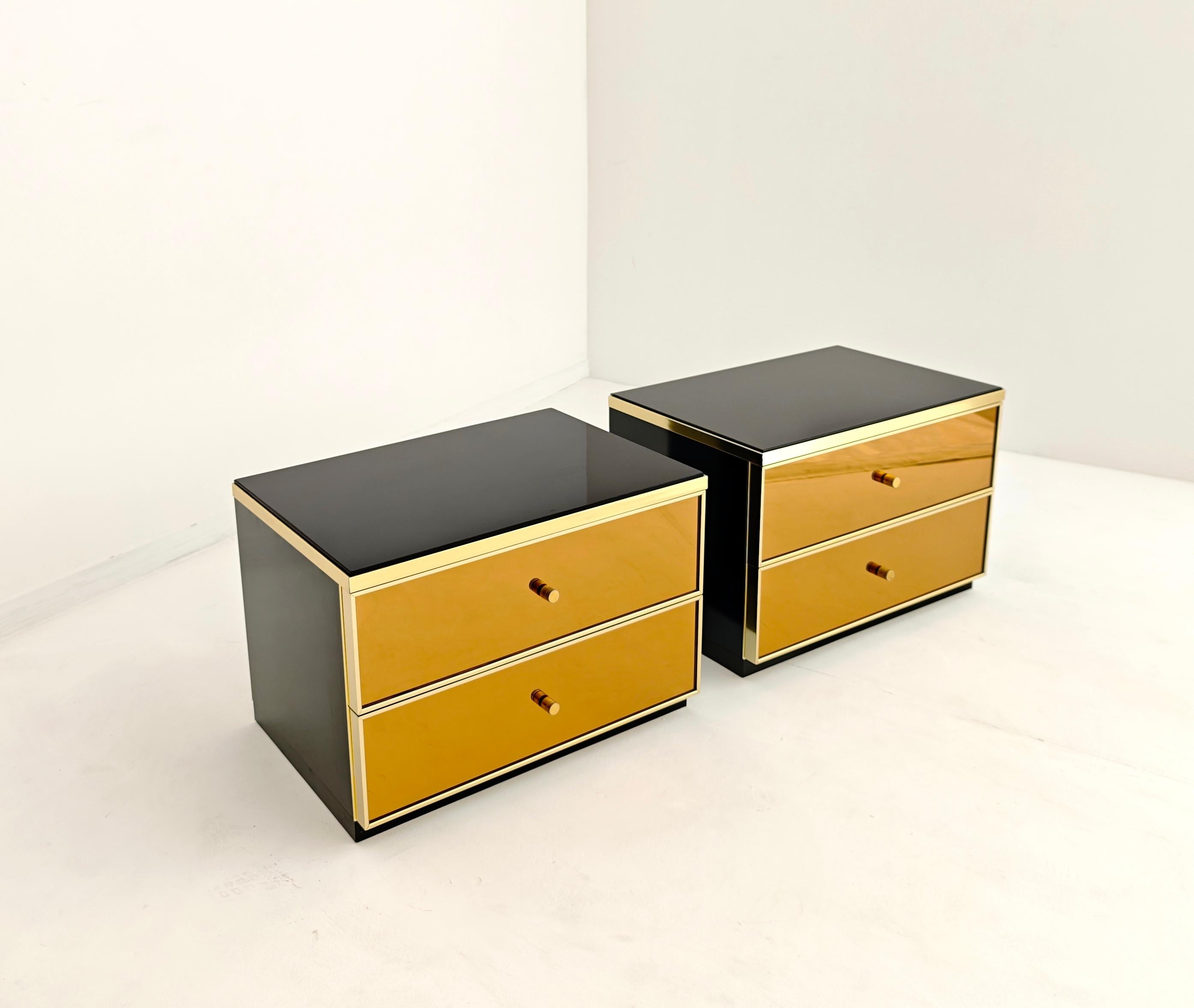 Tables de chevet élégantes conçues par le designer italien Renato Zevi dans les années 1970. Cadre en bois laqué noir, plateau en verre foncé et deux tiroirs en verre miroir bronze avec intérieur en daim noir. Garniture en aluminium doré et boutons