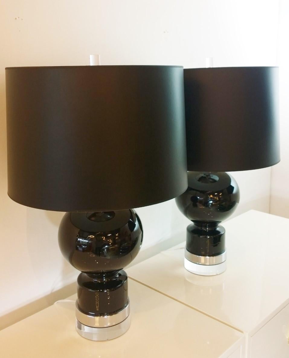 Offered is a pair of Mid-Century Modern shiny black glazed ceramic table lamps with chrome plate accents and chrome plate and Lucite bases and Lucite final. So versatile, this pair could be placed just about anywhere. The Lucite base under the