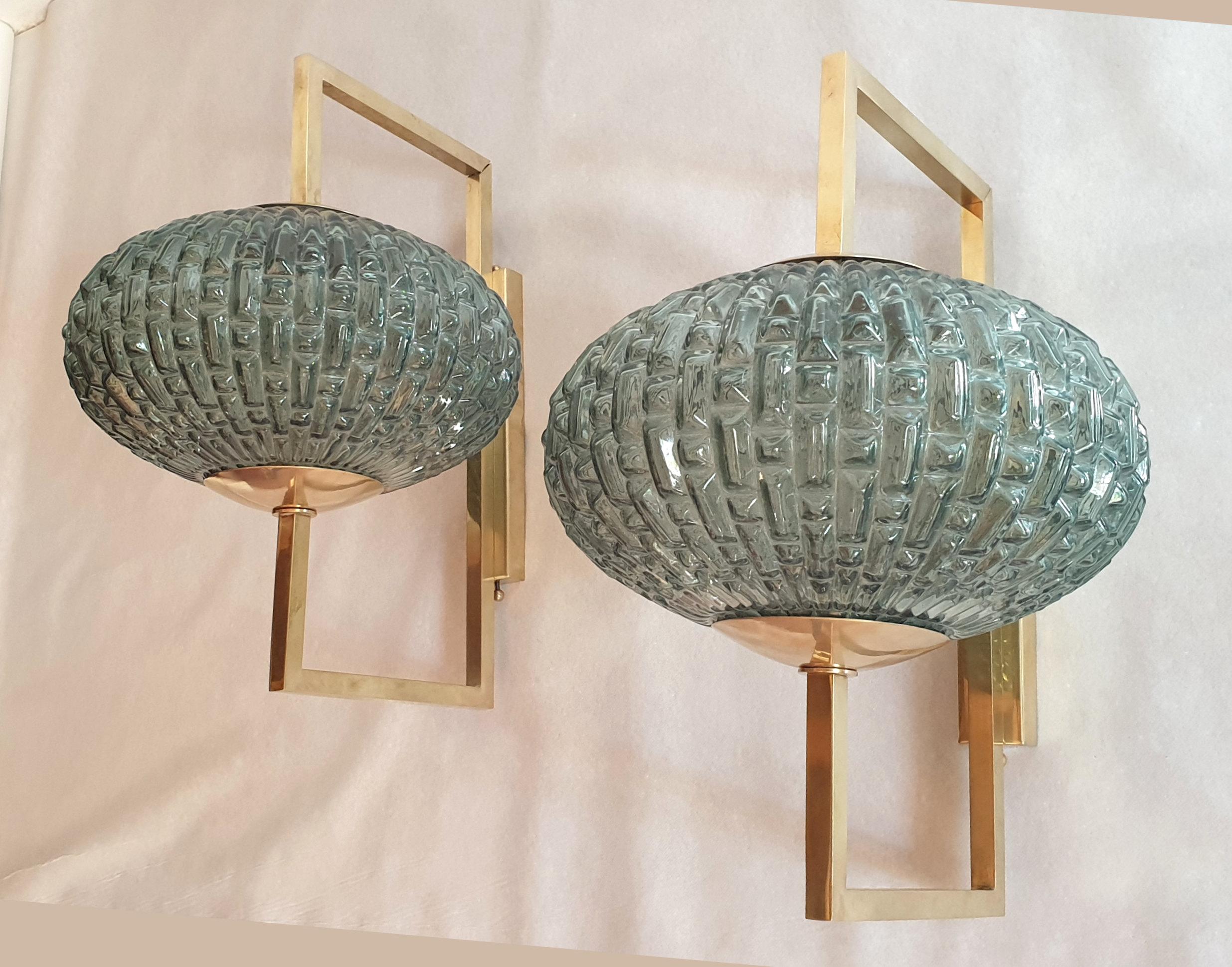 Pair of unusual blue/green Murano glass and brass Mid-Century Modern wall sconces.
One light each, rewired with medium base light bulb.
The brass mounts are sliding up, to ease the light bulb change.
They are in excellent condition.
One glass is