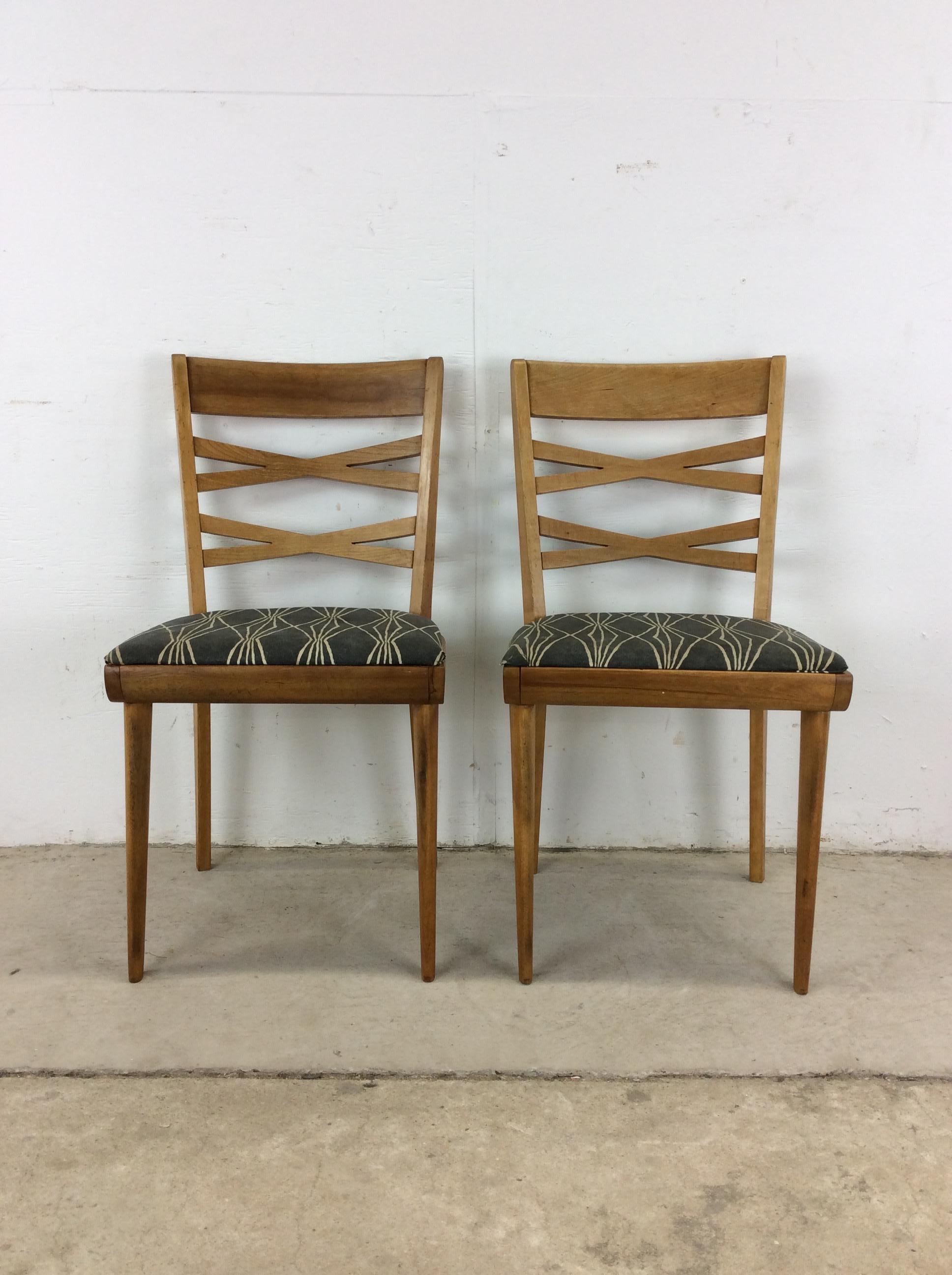 This pair of dining chairs by Heywood Wakefield feature hardwood construction, original champagne finish, newer patterned upholstery, unique double X back, and tall tapered legs.   Please check out our other listings for more Heywood Wakefield