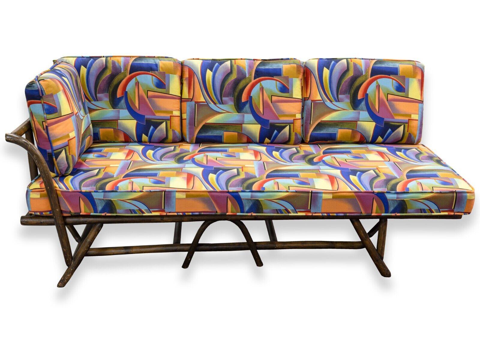 A pair of Ficks Reed bamboo chaise sofas with a funky 90's fabric. This very eclectic pair of chaise sofas are from furniture manufacturer Ficks Reed. The bamboo bases of these chaises are original, but the upholstered fabric is most likely custom