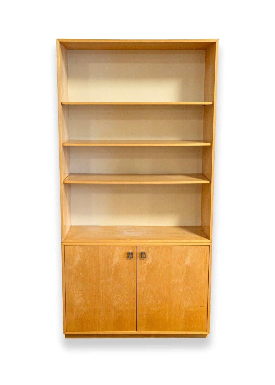 A pair of Founders free standing vintage wood bookshelf. A very sleek bookshelf shelving unit featuring a blonde wood construction with white panel backing. This piece features a free standing design, 4 open shelves, and 2 lower cupboard doors