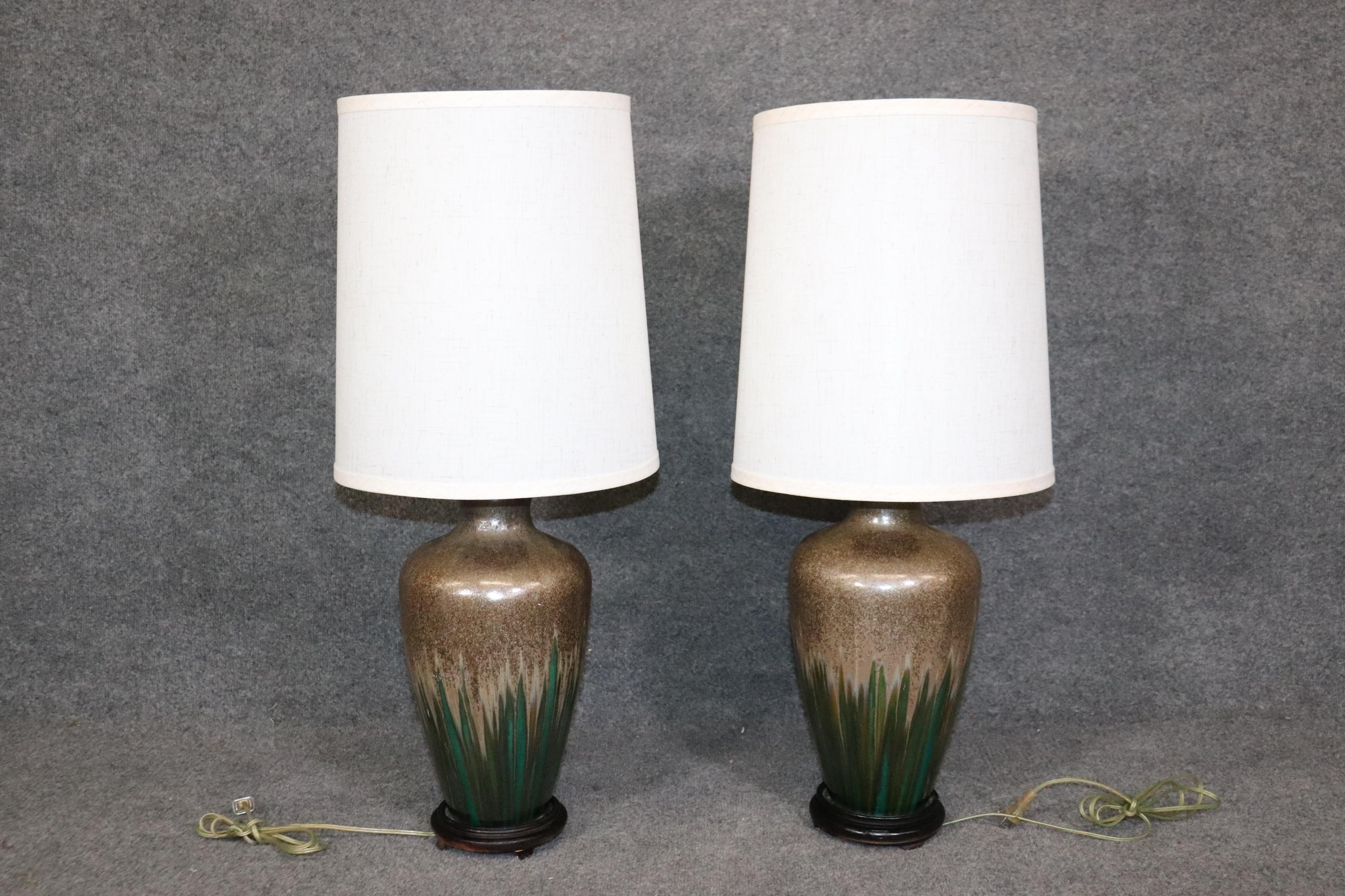 Dimensions- H: 33in W: 14in D: 14in (measurements with shades on) 
This Mid Century Modern Pair of Green Pottery Glazed Table Lamps are truly an interesting example of minimalistic yet luxurious decor. This pair of lamps are crafted of the highest