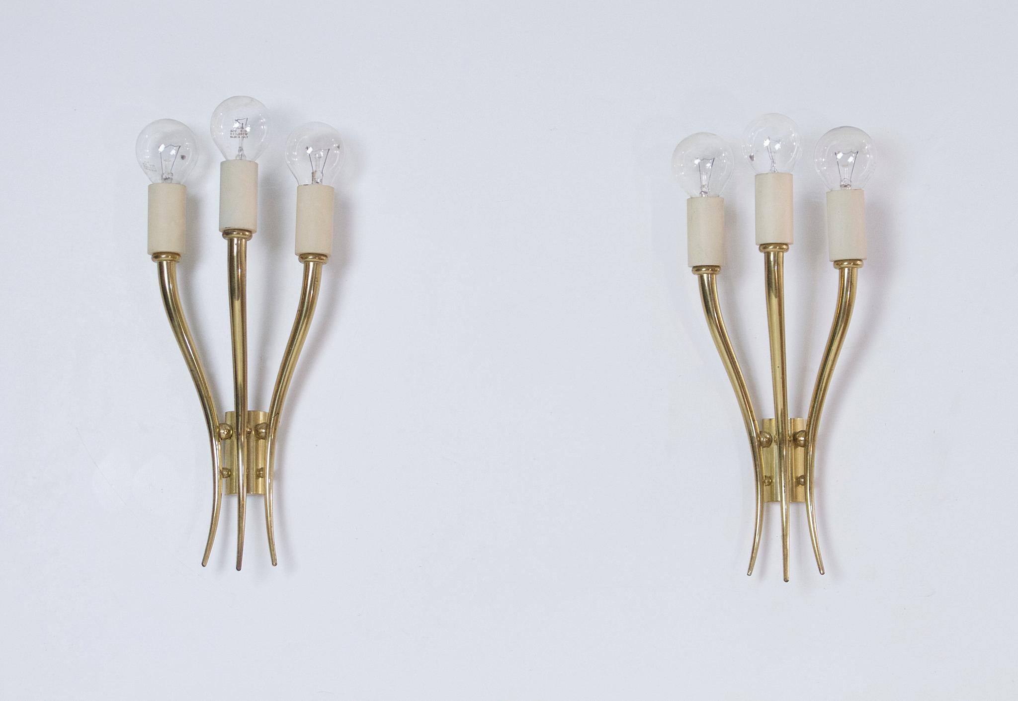 A pair of midcentury wall sconces in brass and ivory white in working condition. Can be used with or without lampshades. Works with E14 lightbulbs.