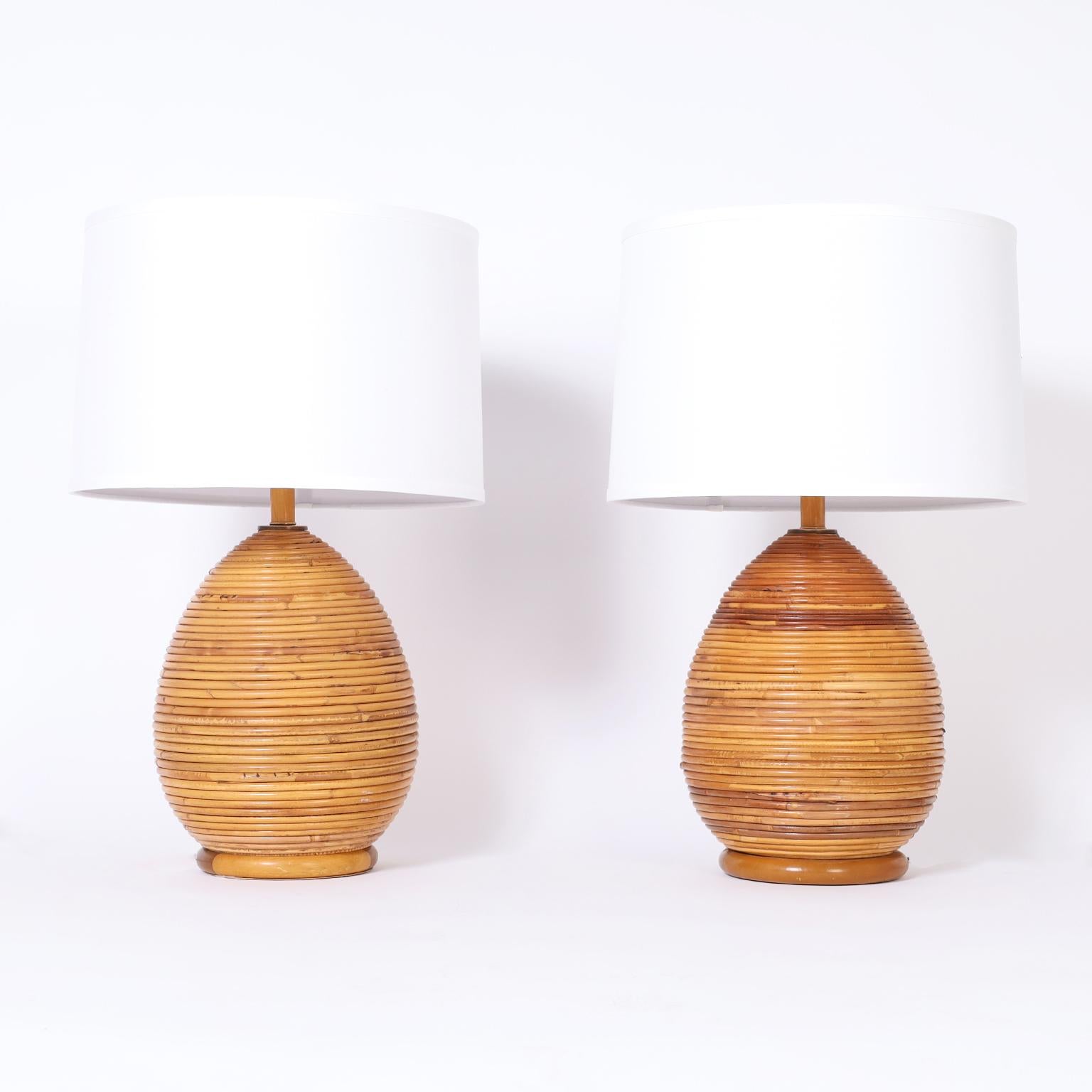 Italian mid-century table lamps crafted with pencil reed or rattan wrapped around classic modern form on round wood bases.