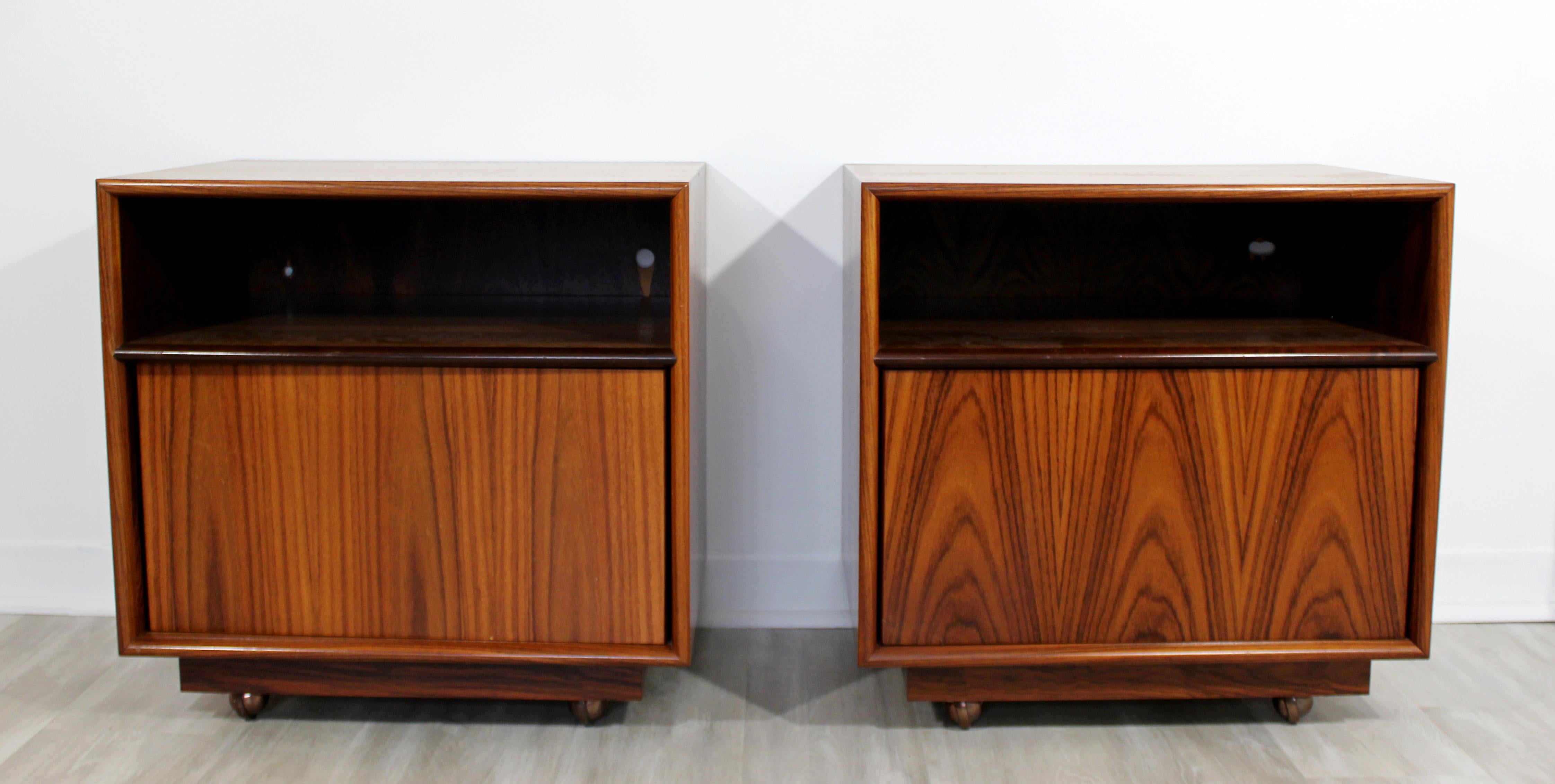 For your consideration is a ravishing, pair of rosewood nightstands, each with a single shelf and door, circa 1960s. In very good vintage condition. The dimensions are 23.5