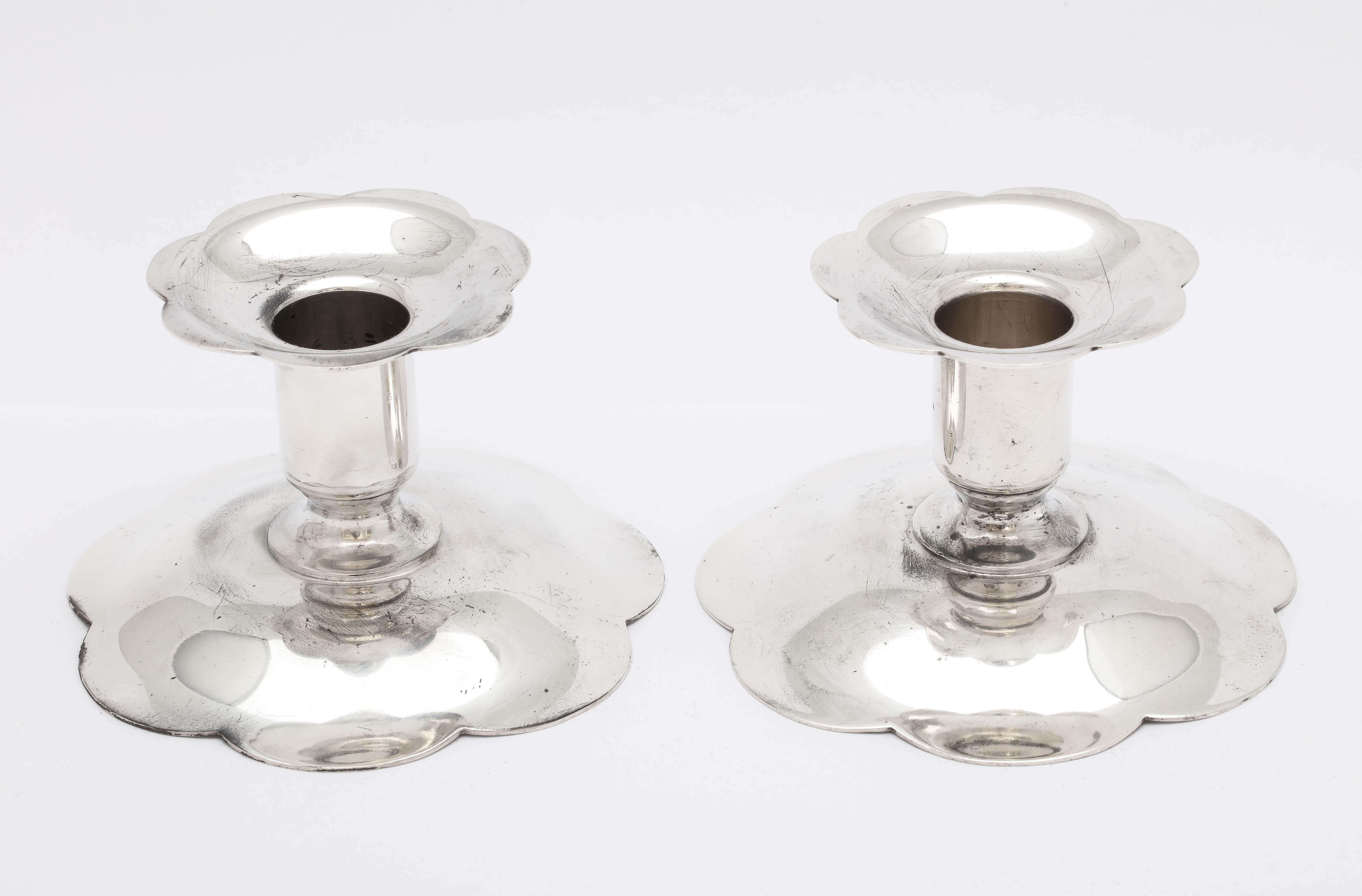 Mid-Century Modern pair of sterling silver candlesticks, Tiffany and Co., New York, circa 1960s. Bases are scalloped in design. Each of the pair measures 2 3/4 inches high x 3 3/4 inches diameter across base. Not weighted, the pair weighs 6.905 troy