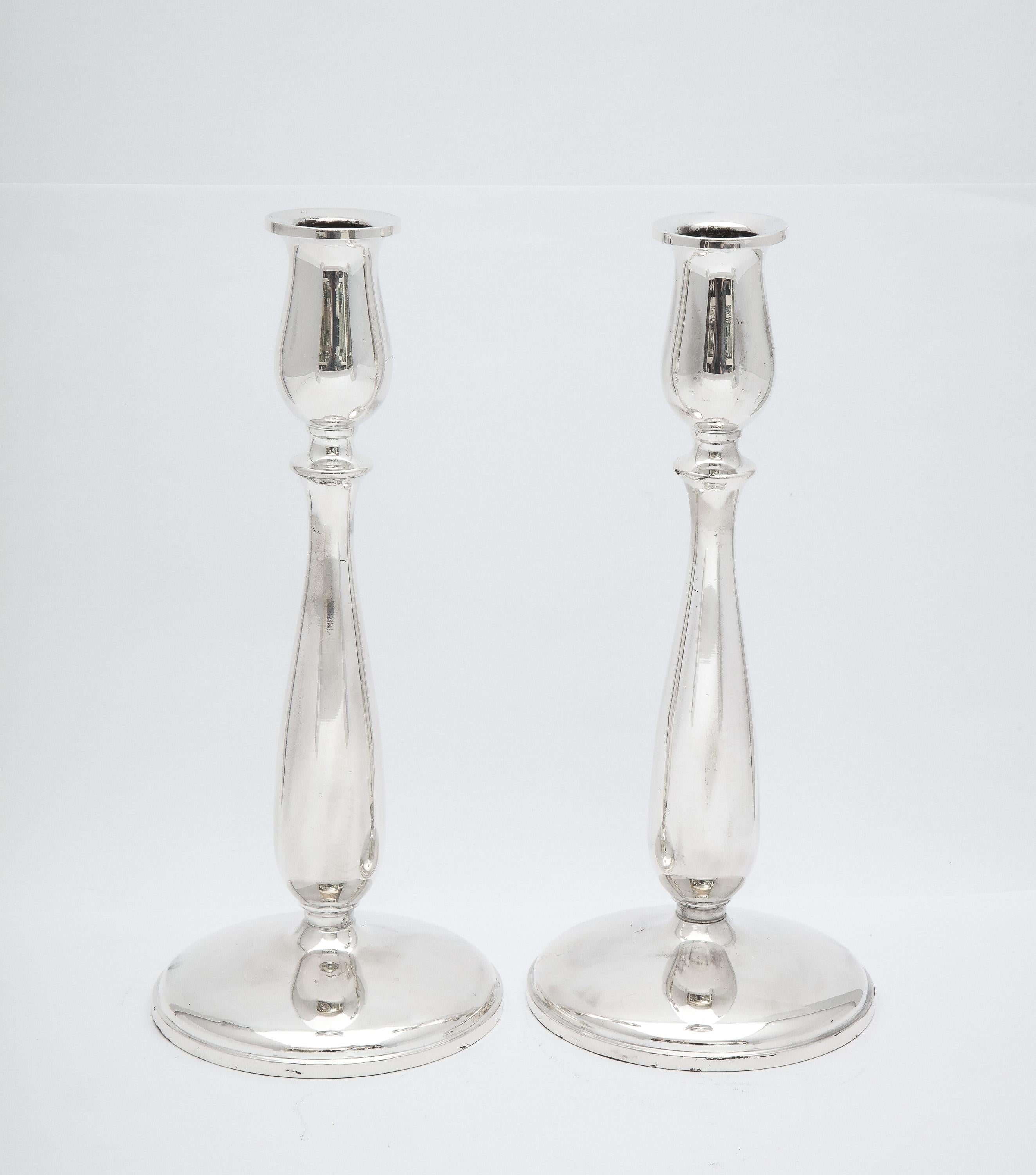 Pair of Mid-Century Modern, sterling silver candlesticks, New York, Ca. 1950's Cartier - maker. Each candlestick measures 9 1/4 inches high x 4 inches diameter across base. Graceful design. Pair comes with the original Cartier felt drawstring