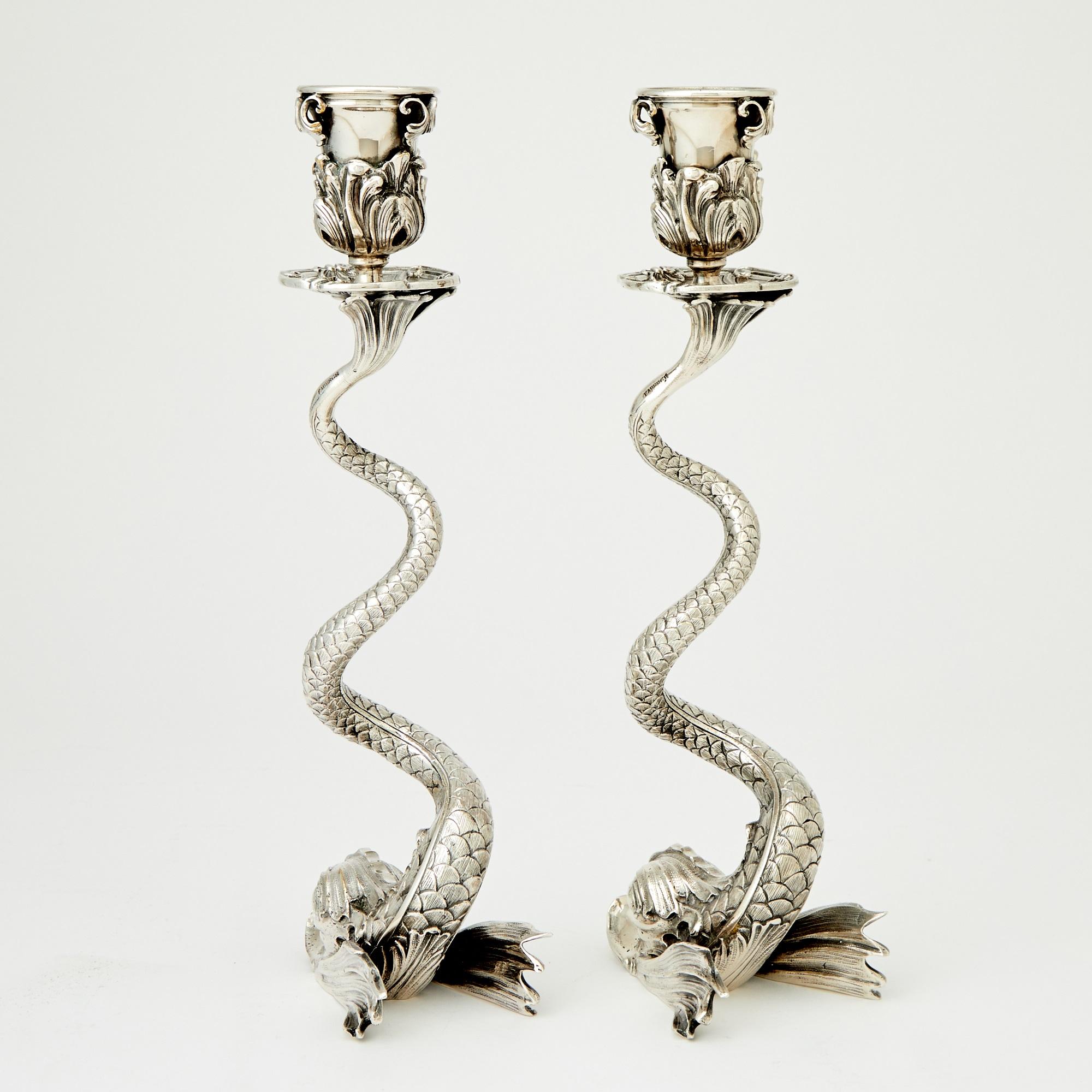 Este excepcional par de portavelas Fabergé de plata de ley, modernos de mediados de siglo, ejemplifica una artesanía exquisita y un diseño atemporal. Cada pieza presenta una escultural base de delfín, bellamente detallada, con el receptáculo del