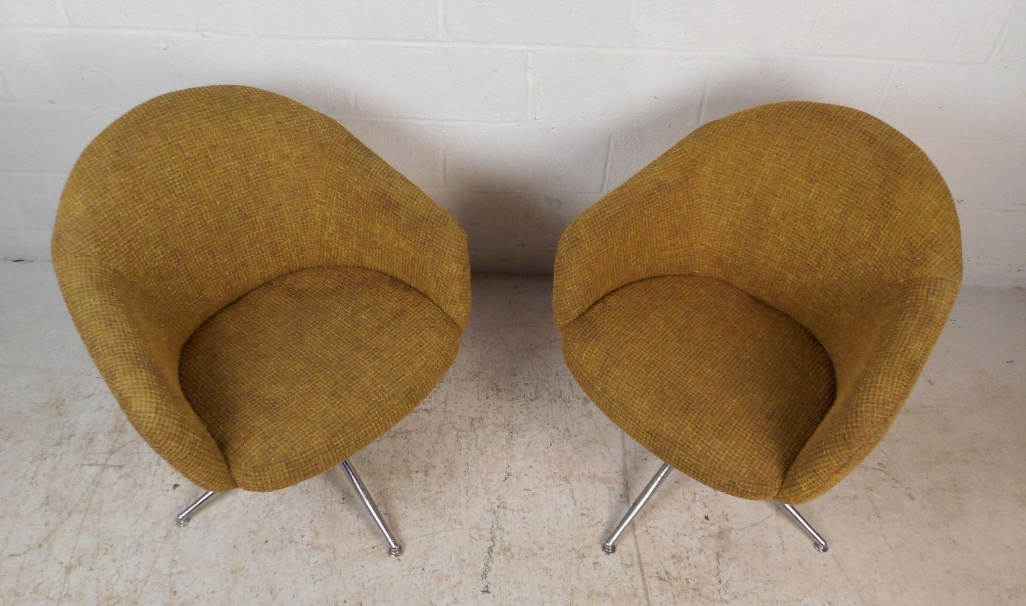This stylish pair of vintage modern swivel chairs feature barrel backrests, winged armrests, and a chrome swivel base with four splayed legs. A sleek and comfortable design covered in a plush gold and green colored upholstery by Viko Baumritter.
