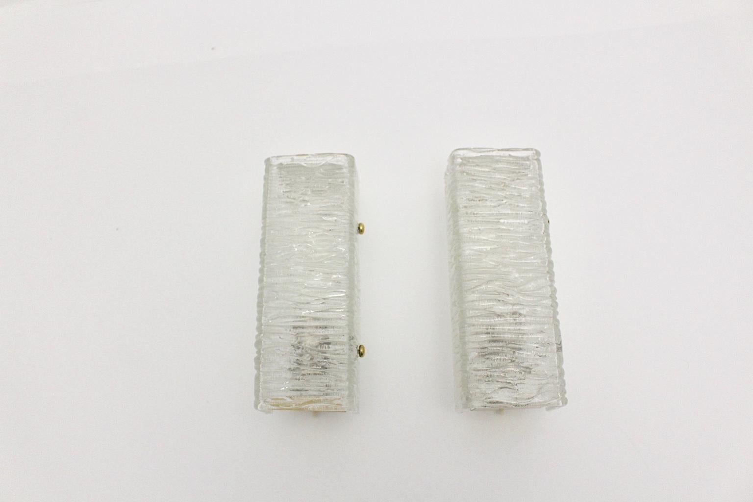 We present a pair of textured glass vintage sconces or wall lights by J. T. Kalmar, which were designed and made in the 1960s in Vienna.
The pair of sconces were made of clear textured glass and shows also brass details and a metal base.
Each