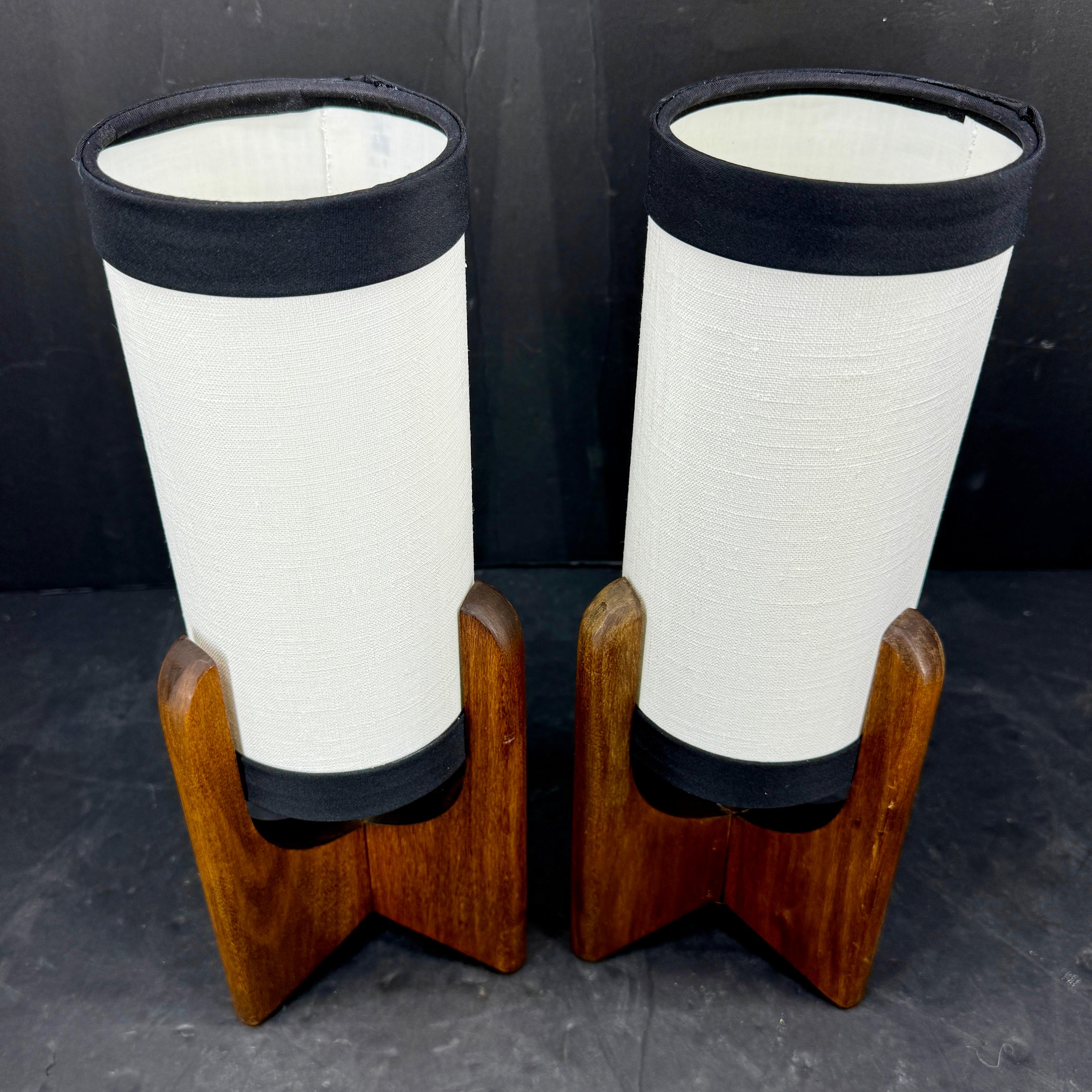 Paire de lampes de table danoises de style moderne du milieu du siècle. Les bases en bois sculpté maintiennent ces lampes d'une manière artistique et gracieuse. Les teintes sont ivoire avec une bande marine et sont neuves. Les lampes sont classiques