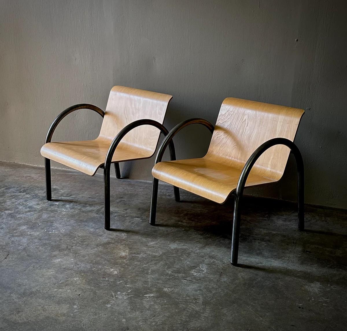 This set of four midcentury modern armchairs combines sleek metal frames with elegantly curved bentwood elements, showcasing the minimalist aesthetic typical of French design from the era. The light blond wood grain provides a stunning visual