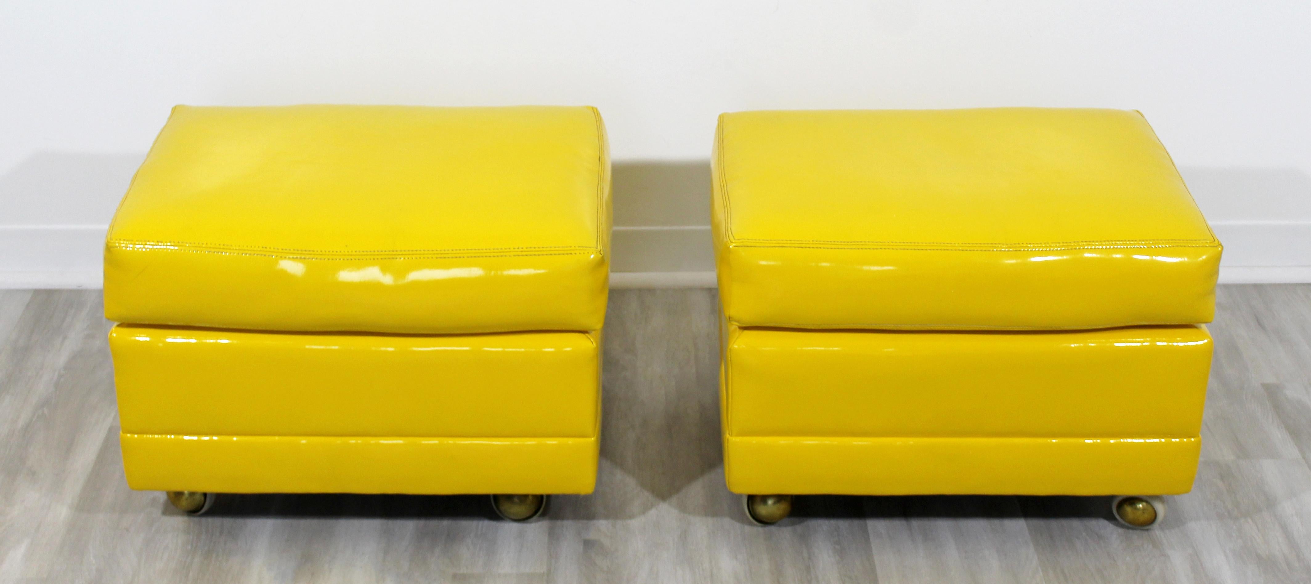 For your consideration is a slick pair of ottomans or seats on casters, upholstered in yellow patent leather vinyl, circa 1970s. In excellent vintage condition. The dimensions are 22