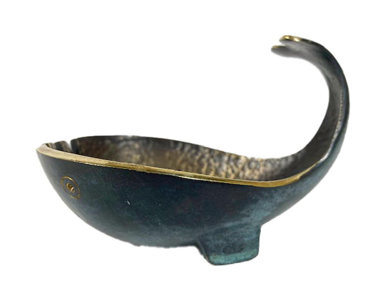 Modernist cast bronze ashtray in the form of a stylized whale with its fluke raised resting on its pectoral fins. The interior with a hammered surface and the exterior with an applied mottled green patina.