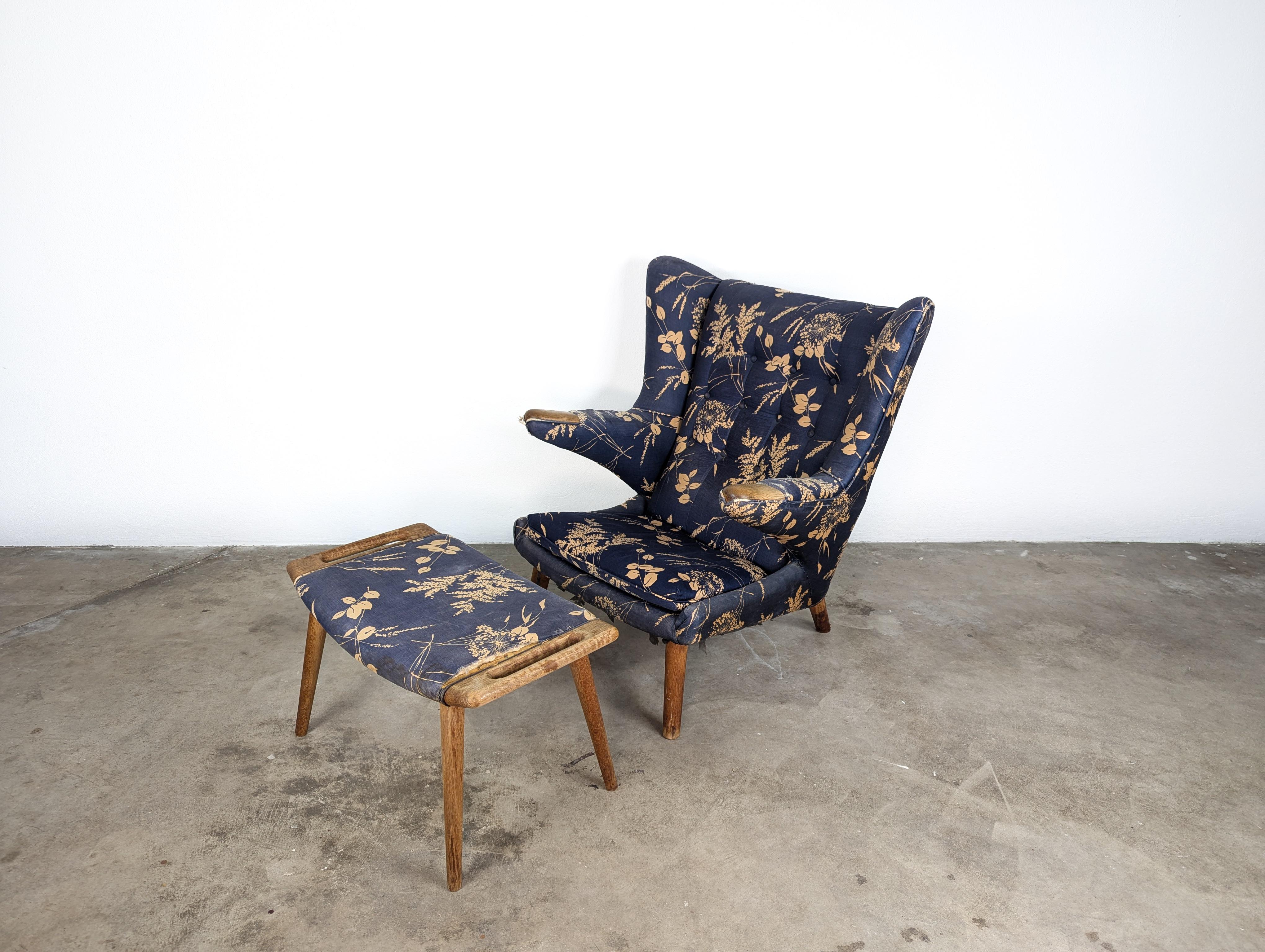 Sweep into the classic, timeless appeal of mid-century modern design with this authentic Hans Wegner Papa Bear Chair and Ottoman. Both pieces were manufactured by the renowned A.P. Stolen in the 1950s, one of the golden ages of Danish furniture
