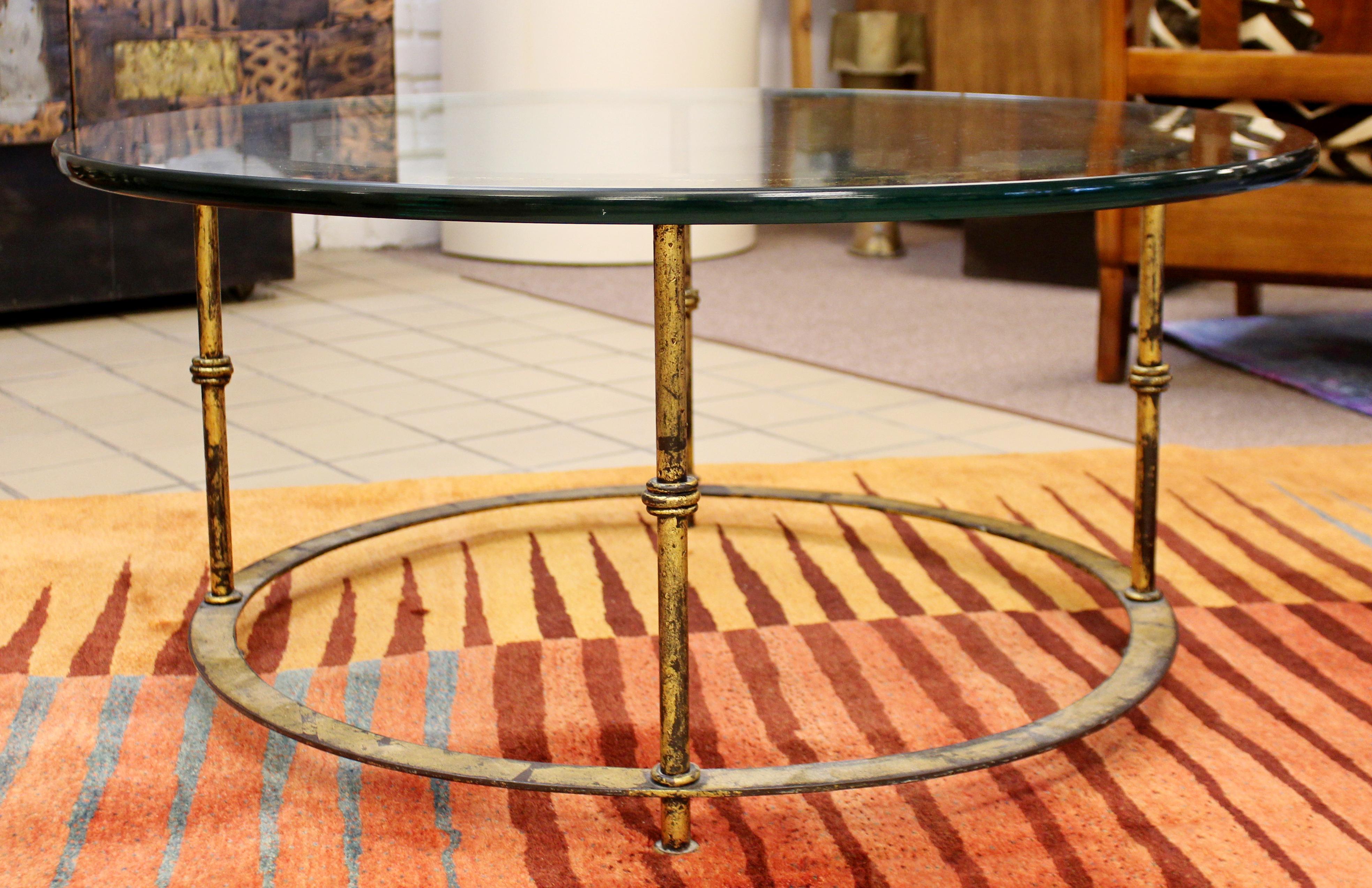 For your consideration is a beautiful, round coffee table, with a glass top on a patinated brass base, circa the 1960s. In excellent vintage condition. The dimensions are 36