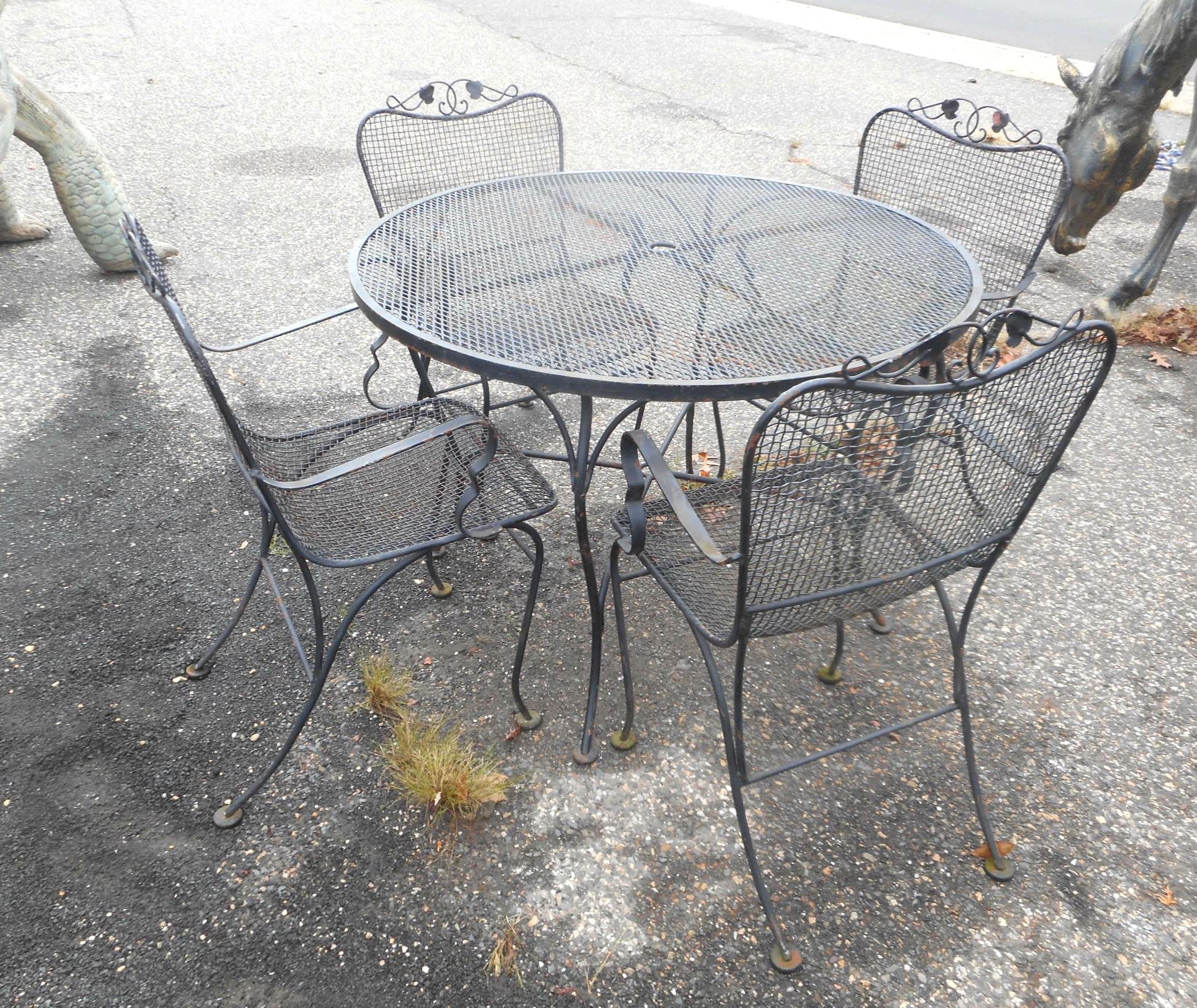 This beautiful vintage modern patio set includes four dining chairs, a round dining table, and two love seats. Sleek design with floral detail, sculpted iron frames, and mesh seating. The bent wrought iron frame and wonderful contours ensure plenty
