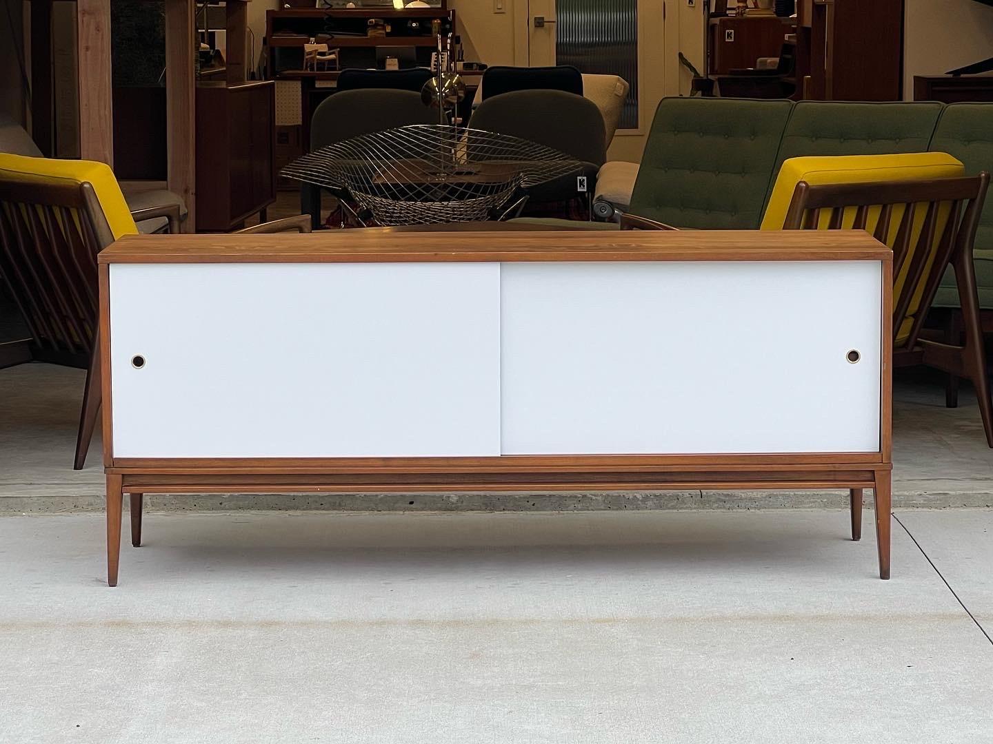 Mid century modern Paul McCobb for Planner Group maple credenza with white lacquer sliding doors and brass circular pulls. A phenomenal credenza that’s timeless in design and by a very notable designer that still evolves the design world to this