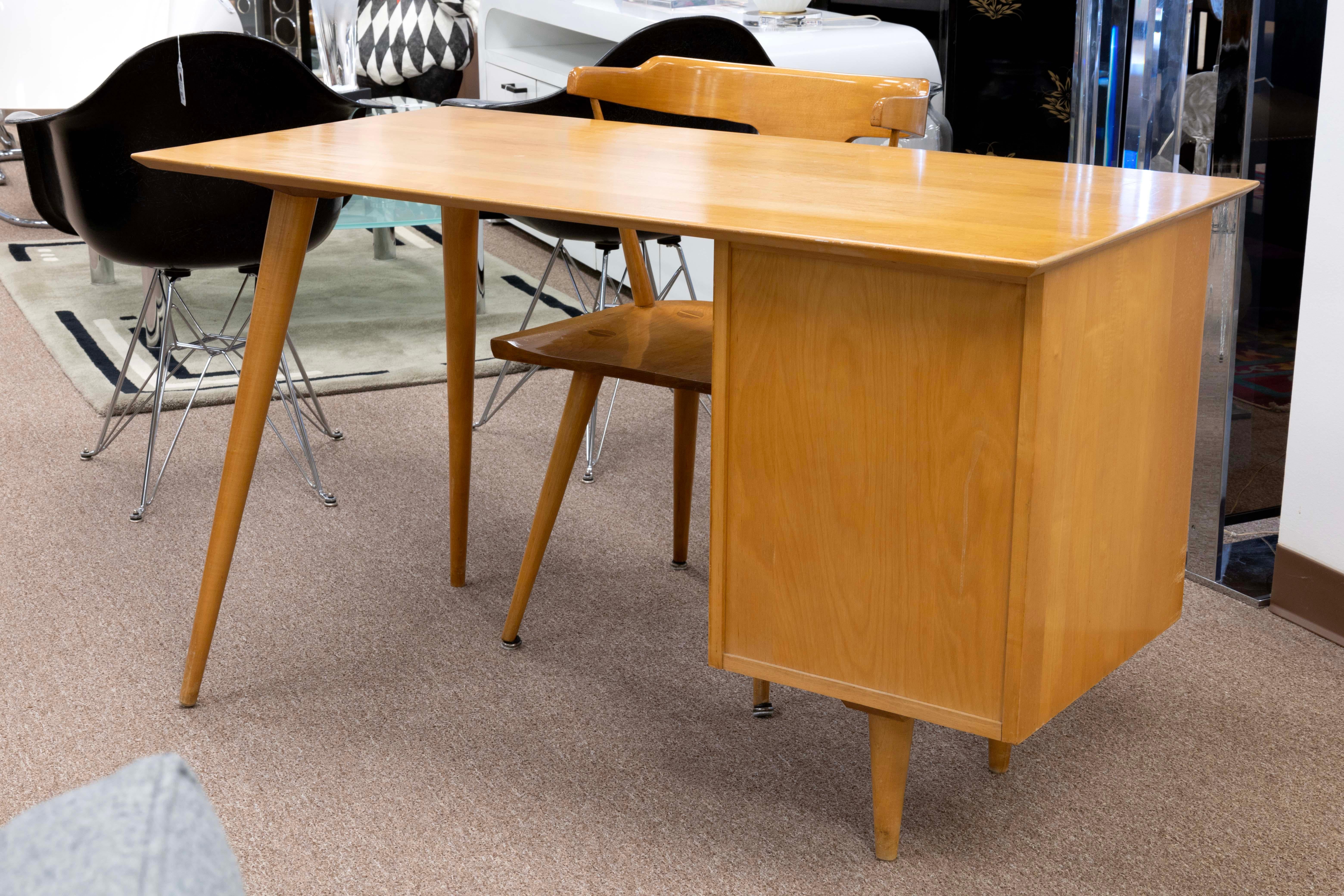 This Classic Mid-Century Modern Paul McCobb planner desk and chair is a timeless piece that will never go out of style. The desk features an maple wood top with two drawers for convenient storage space. The drawers are framed with solid wood edges