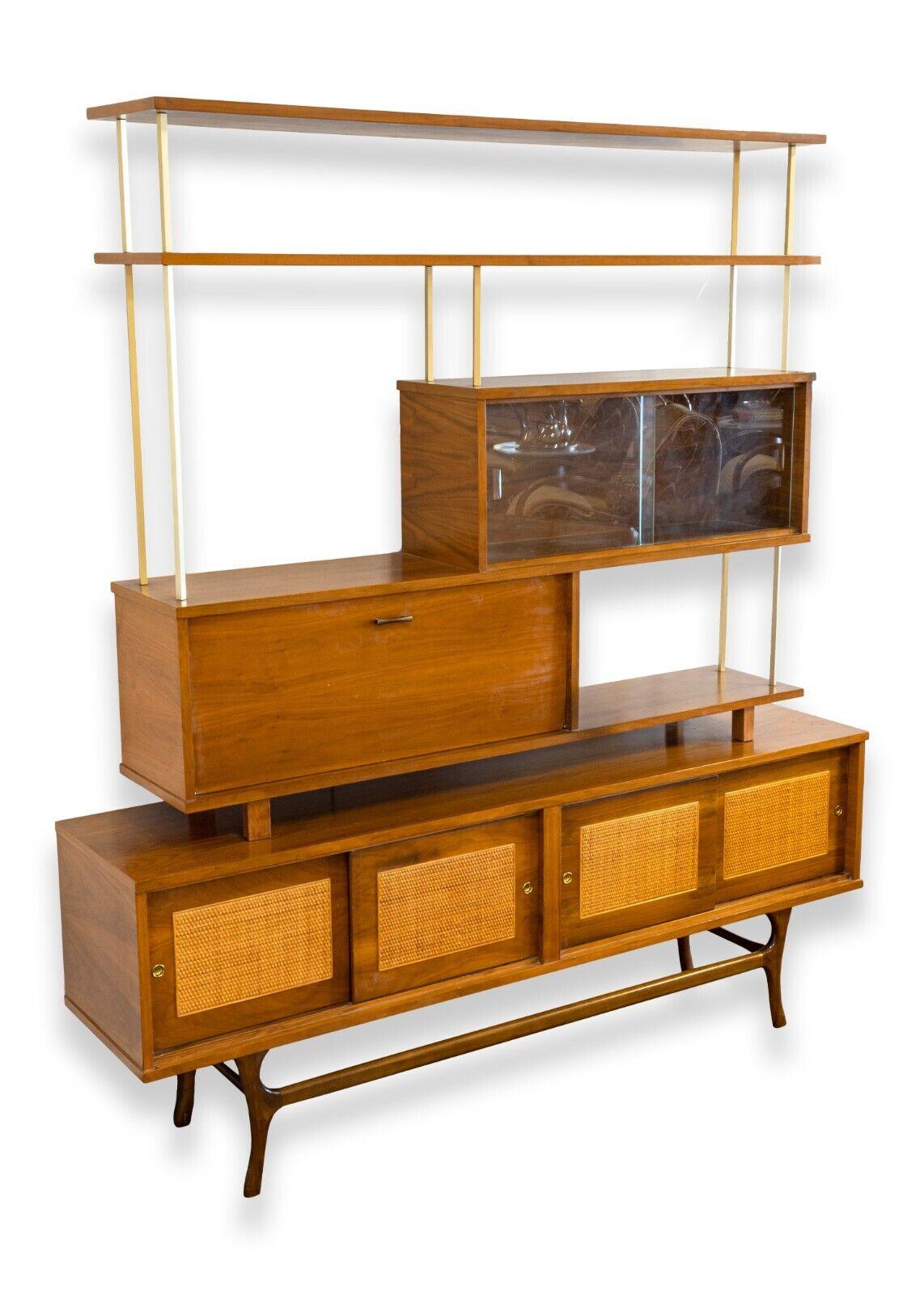 A Paul McCobb style wall unit by James Philips. This absolutely stunning wall unit features an all wood construction with five shelves and four different cabinets. The top cabinet features two sliding glass doors. The middle cabinet features a drop