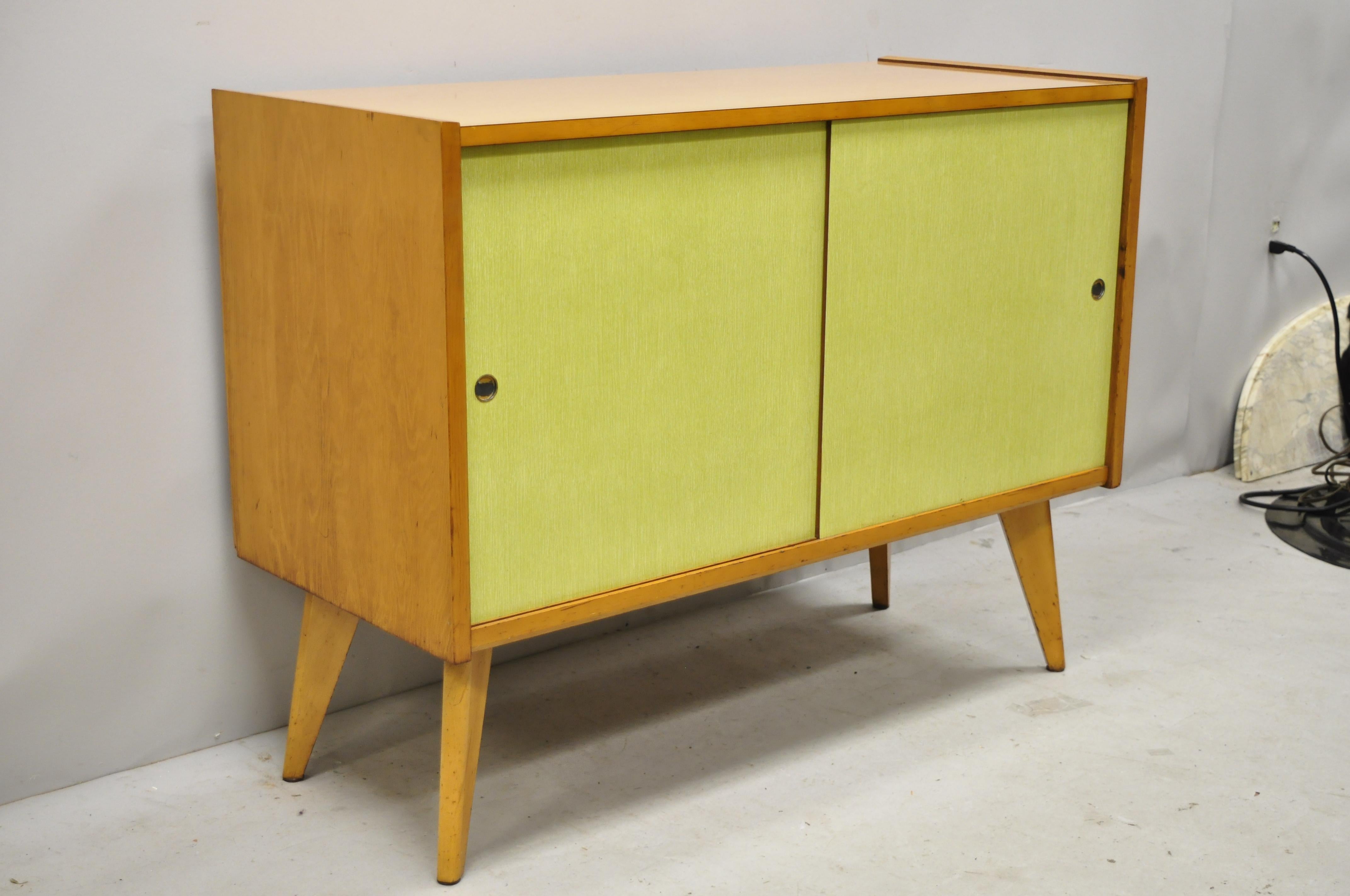 Mid-Century Modern Paul McCobb style sliding door yellow credenza cabinet buffet. Item features yellow sliding Masonite doors, laminate top, 1 drawer, angled tapered legs, clean modernist lines, quality American craftsmanship, sleek sculptural form,
