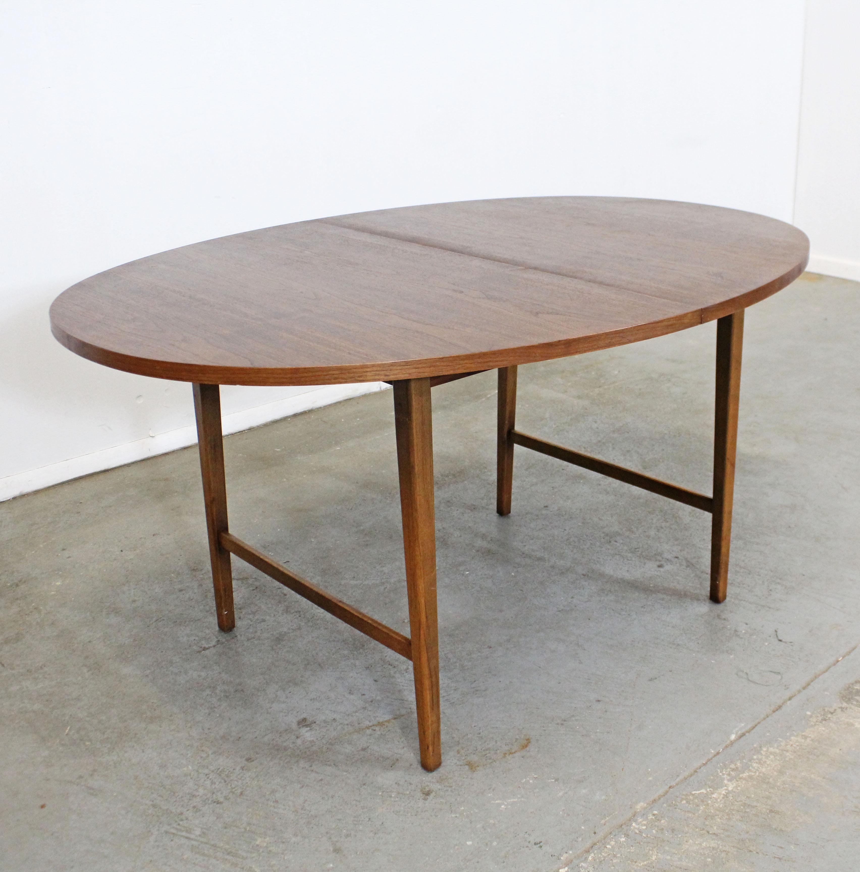 Offered is a round vintage Mid-Century Modern dining table attributed to Paul McCobb. This is a walnut dining table with a round top, includes one 12