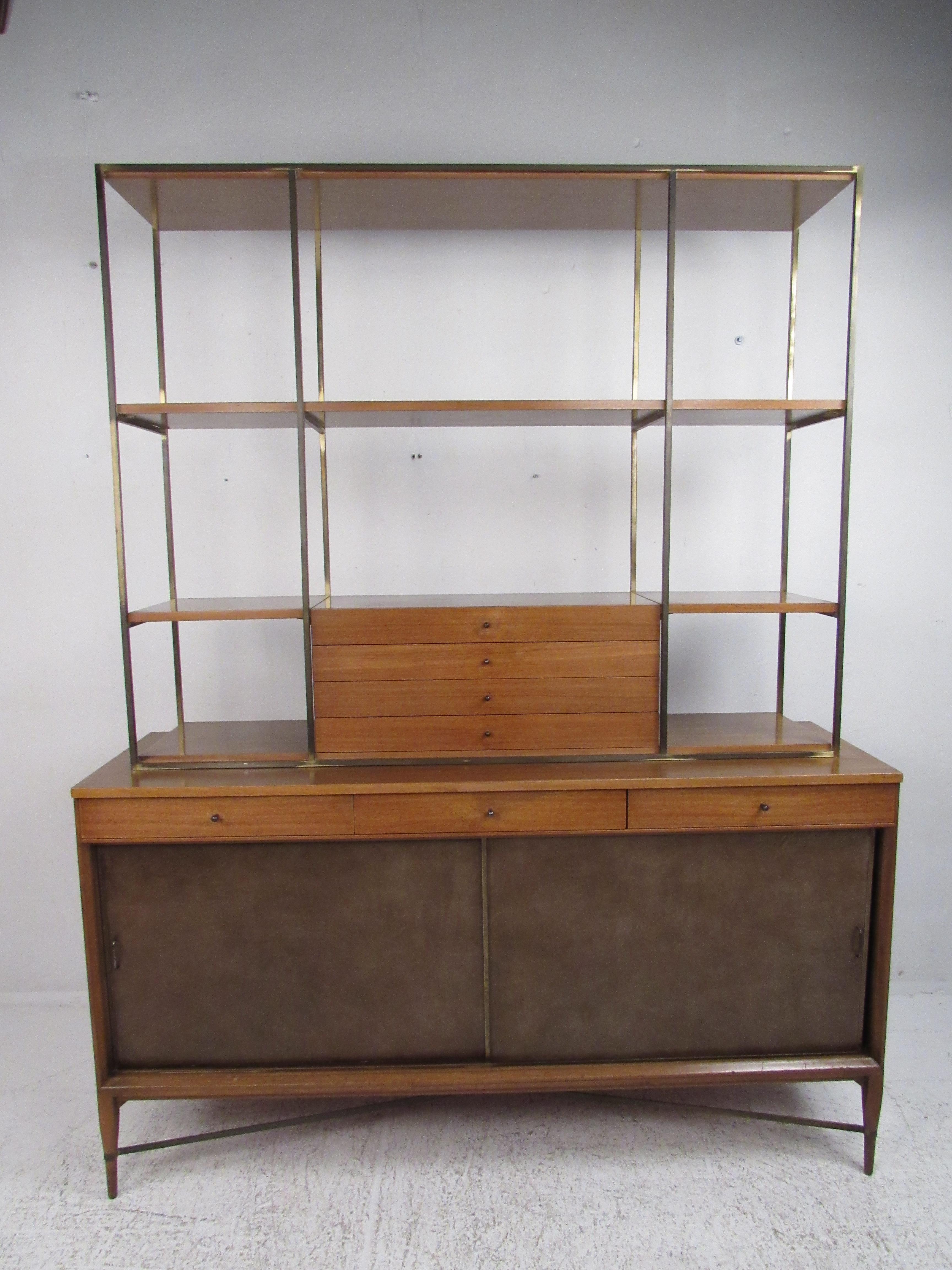 A beautiful vintage modern buffet with a breakfront by Paul McCobb for Calvin. This two-piece hutch features a sliding door credenza with three drawers and an elegant display topper with a brass frame. This piece offers plenty of room for storage