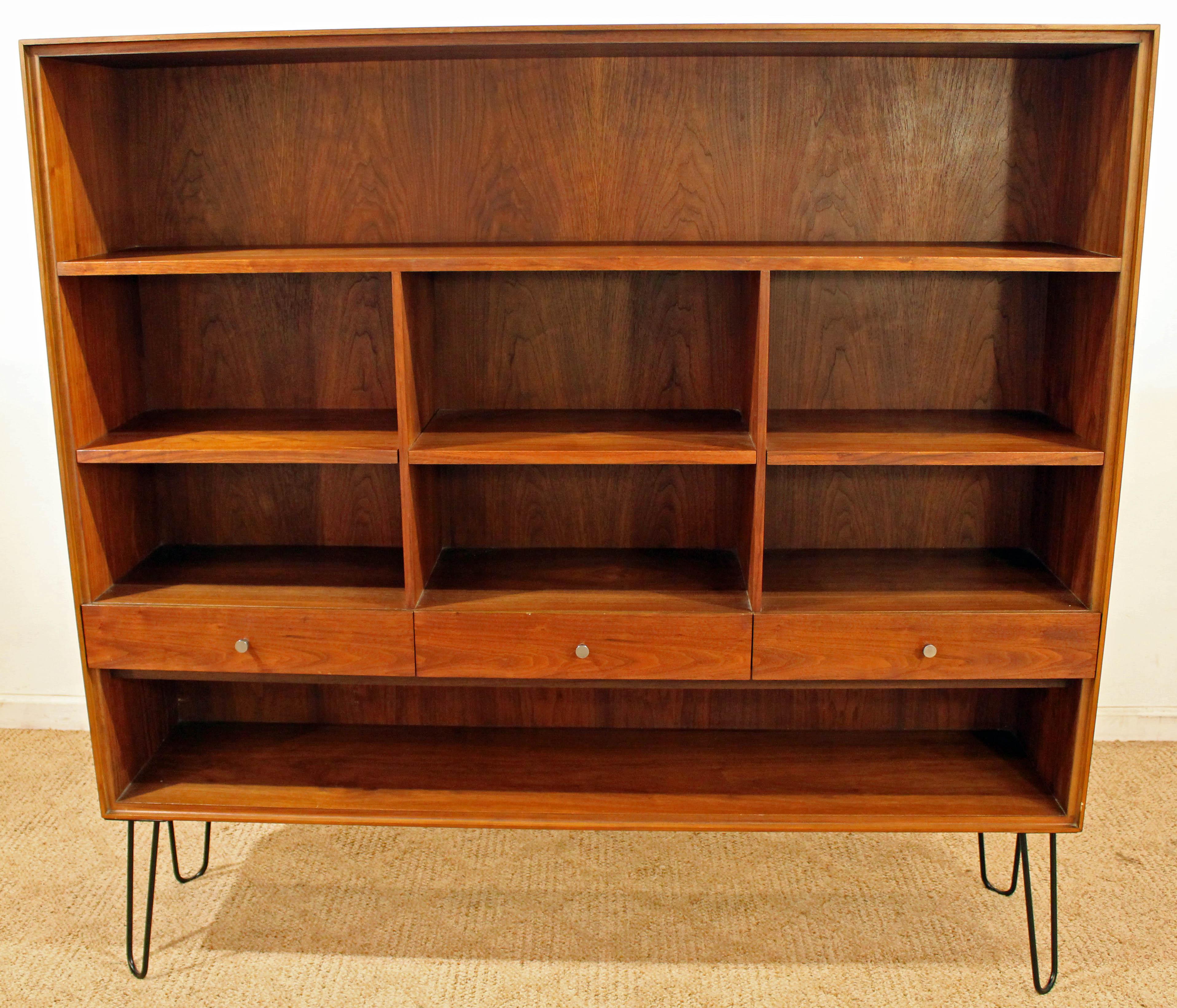 Offered is a piece of time and design: a Mid-Century Modern bookcase on hairpin legs. This piece was originally a hutch top, designed by Paul McCobb 'Declaration' by Lane. Metal legs have been added. It is made of walnut, with multiple shelves and