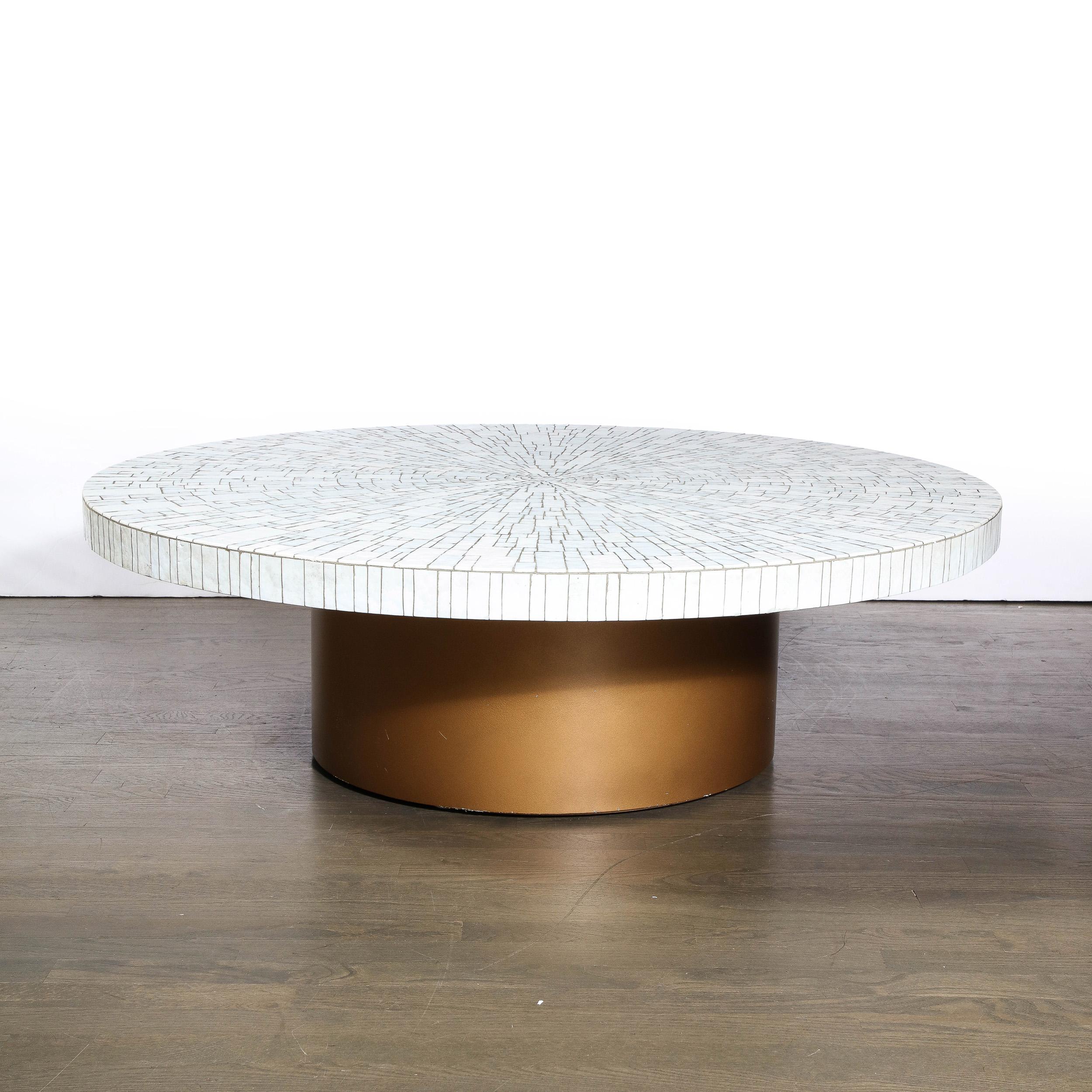 This stunning and sophisticated Mid-Century Modern cocktail table was realized in France, circa 1960. It features a cylindrical base created finished in a sumptuous antique gilt and topped with a circular tile mosaic top full of verve and subtle