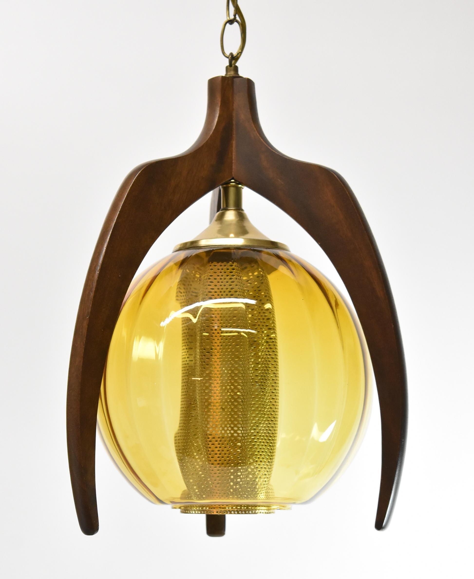 Mid Century Modern hanging pendant light. Walnut three point frame with round amber glass globe shade. Single socket. Circa 1960's by Pearsall. Dimensions: 16.5