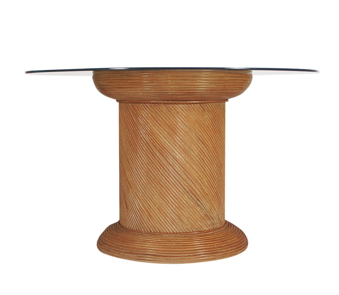 Table de salle à manger en roseau de forme A. Il se compose d'une base de tambour enveloppée de bambou et d'un grand plateau en verre transparent.