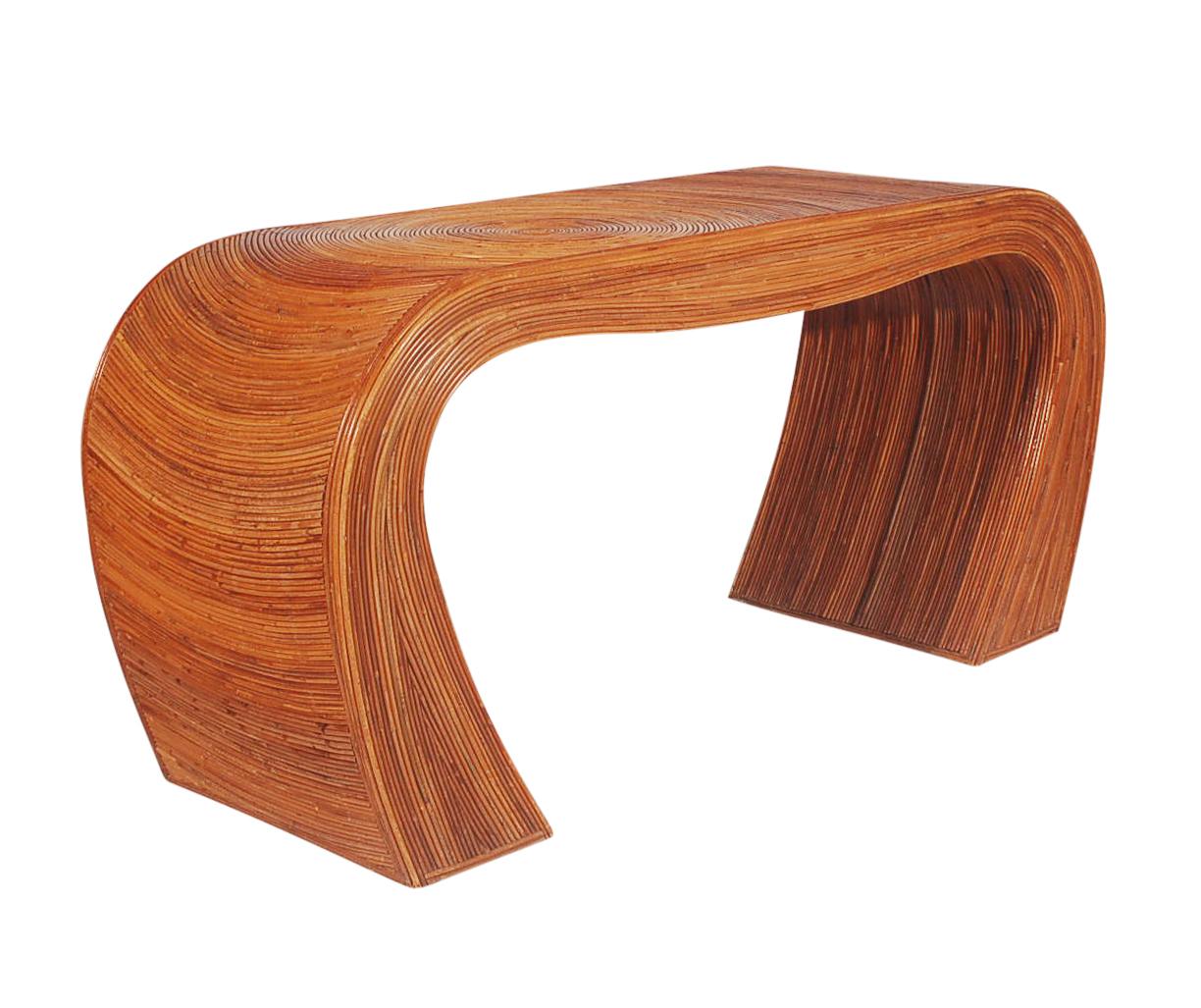 A sculptural pencil reed coffee table. It features wood construction with pencil reed bamboo design work.