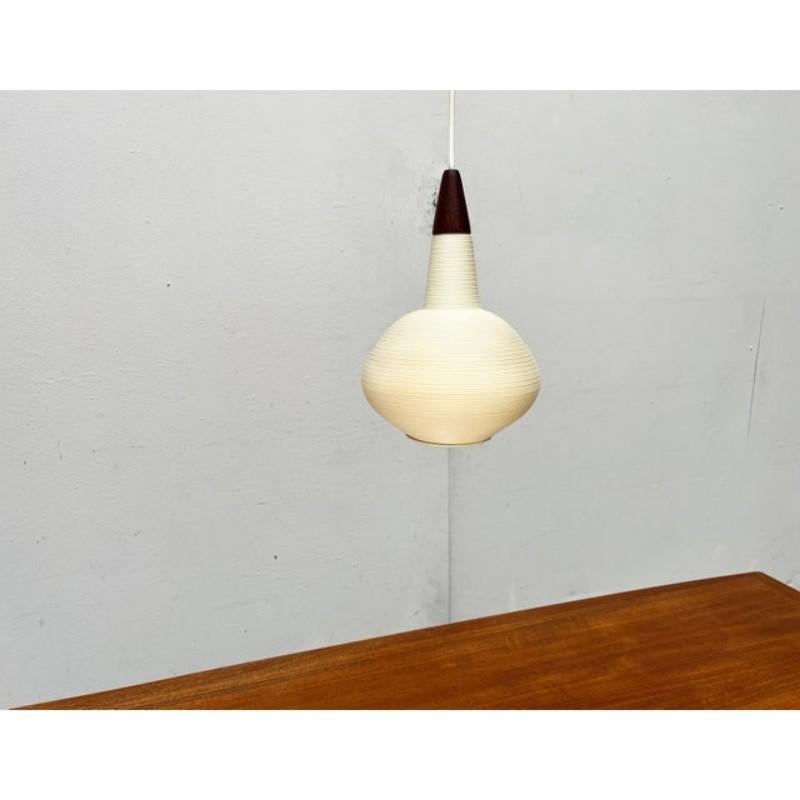 Simple Rotaflex pendulum based on a design by Yasha Heifetz from the 1960s.

Minimalist pendant lamp made of plastic and wood. The symmetrical lamp body is made of a translucent plastic (Rotaflex) and has a groove structure all around. The top made