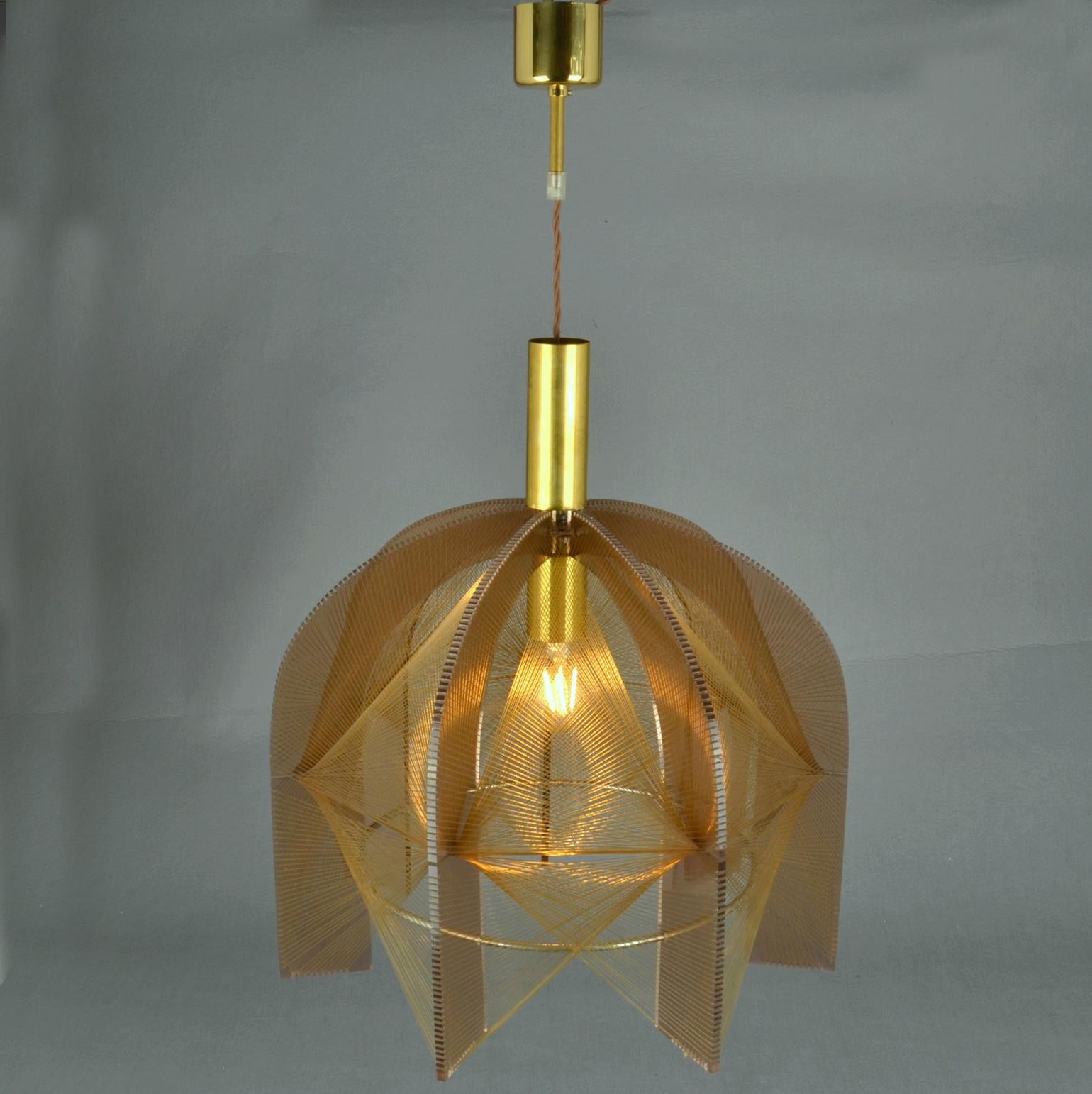 Lampada scultorea in perspex bronzo e filo trasparente accompagnata da un supporto interno in ottone e un anello in nichel. Il design è influenzato dall'artista e scultore pioniere dell'Avant Garde Naum Gabo (1890-1977). 
Queste lampade sono