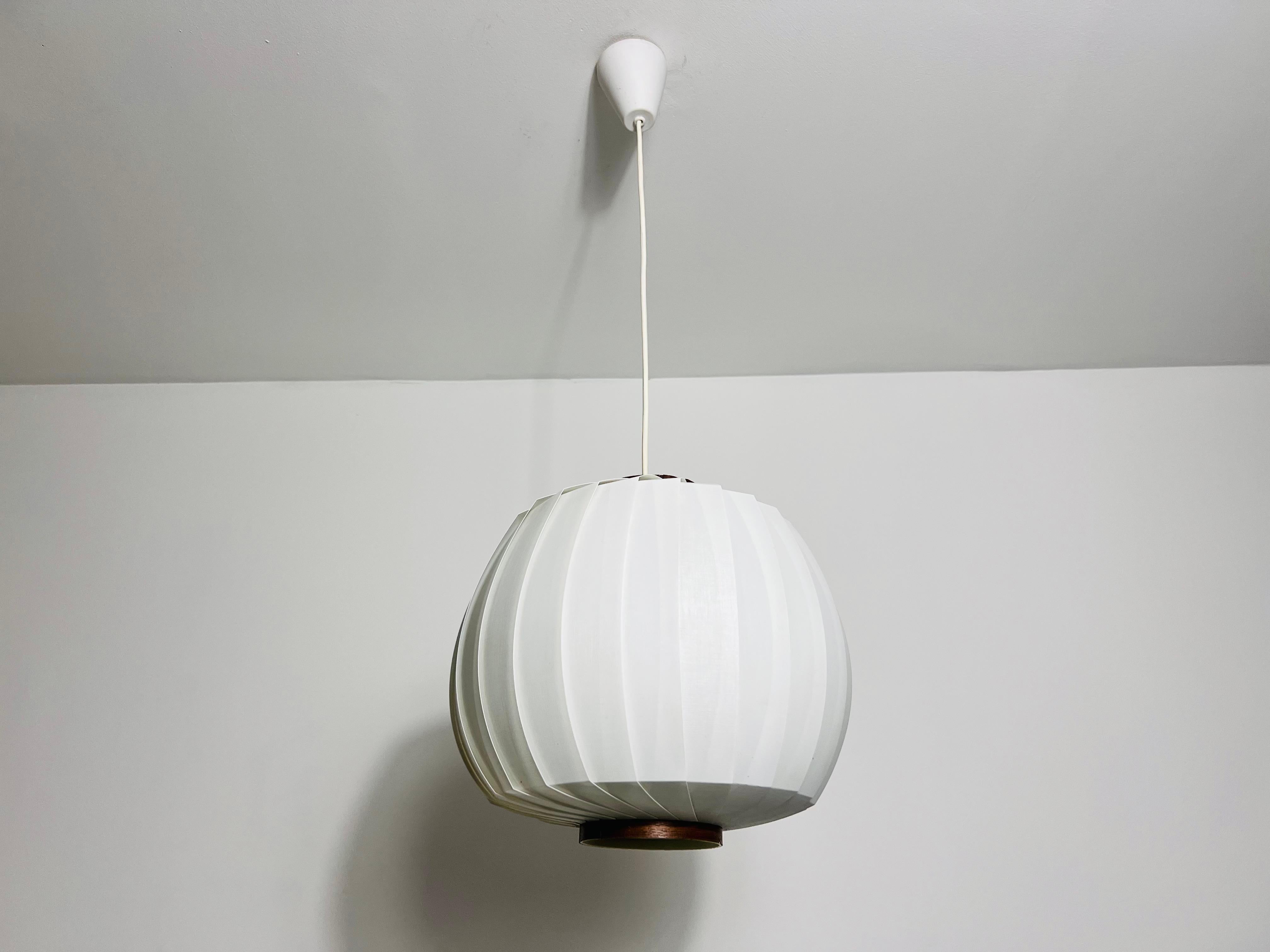 Wir präsentieren eine Hängeleuchte aus den 1960er Jahren, die minimalistisches italienisches Design mit einem extravaganten und seltenen Design verkörpert. Diese elegante Leuchte hat eine organische Form und strahlt ein warmes Licht aus, das eine