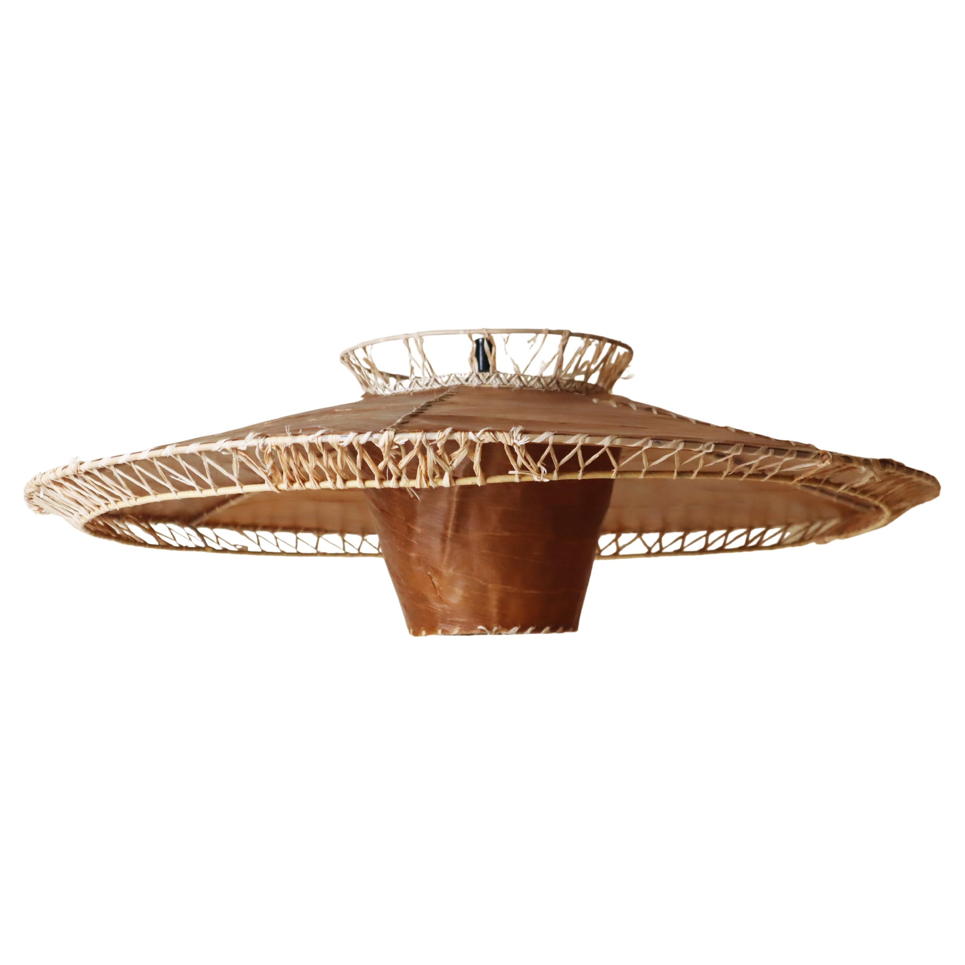 Questa graziosa lampada a sospensione è un vero e proprio gioiello con il suo design anni '50. La lampada è realizzata con materiali naturali; credo si tratti di foglie simili alla pelle tagliate a mano e cucite insieme alla paglia. Abbiamo