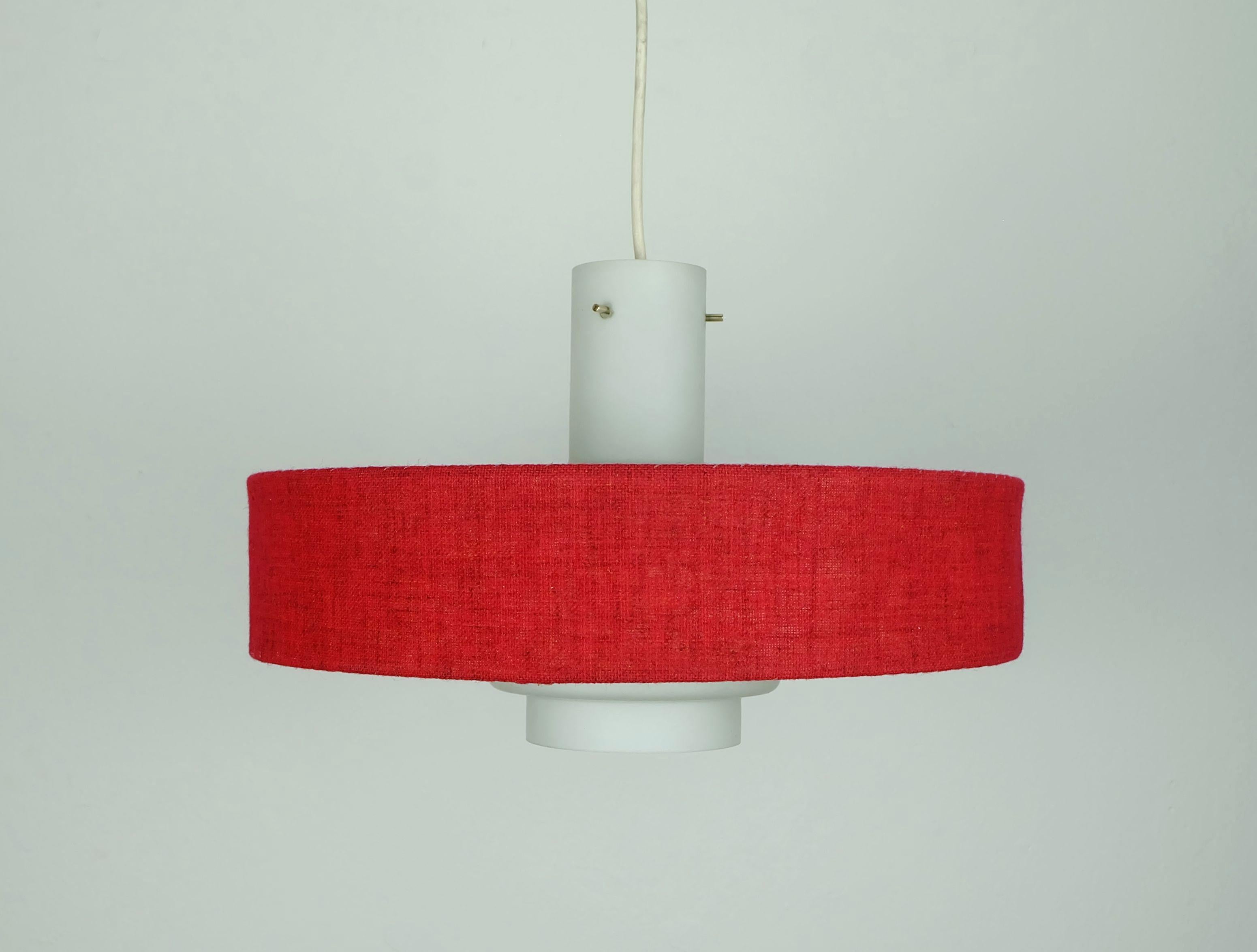Lampada a sospensione degli anni '60 molto bella ed elegante. Il paralume è composto da due parti, un vetro opalino bianco all'interno e un tessuto rosso (hopsack) su carta, mentre la parte superiore è costituita da un foglio di plastica bianco. Per