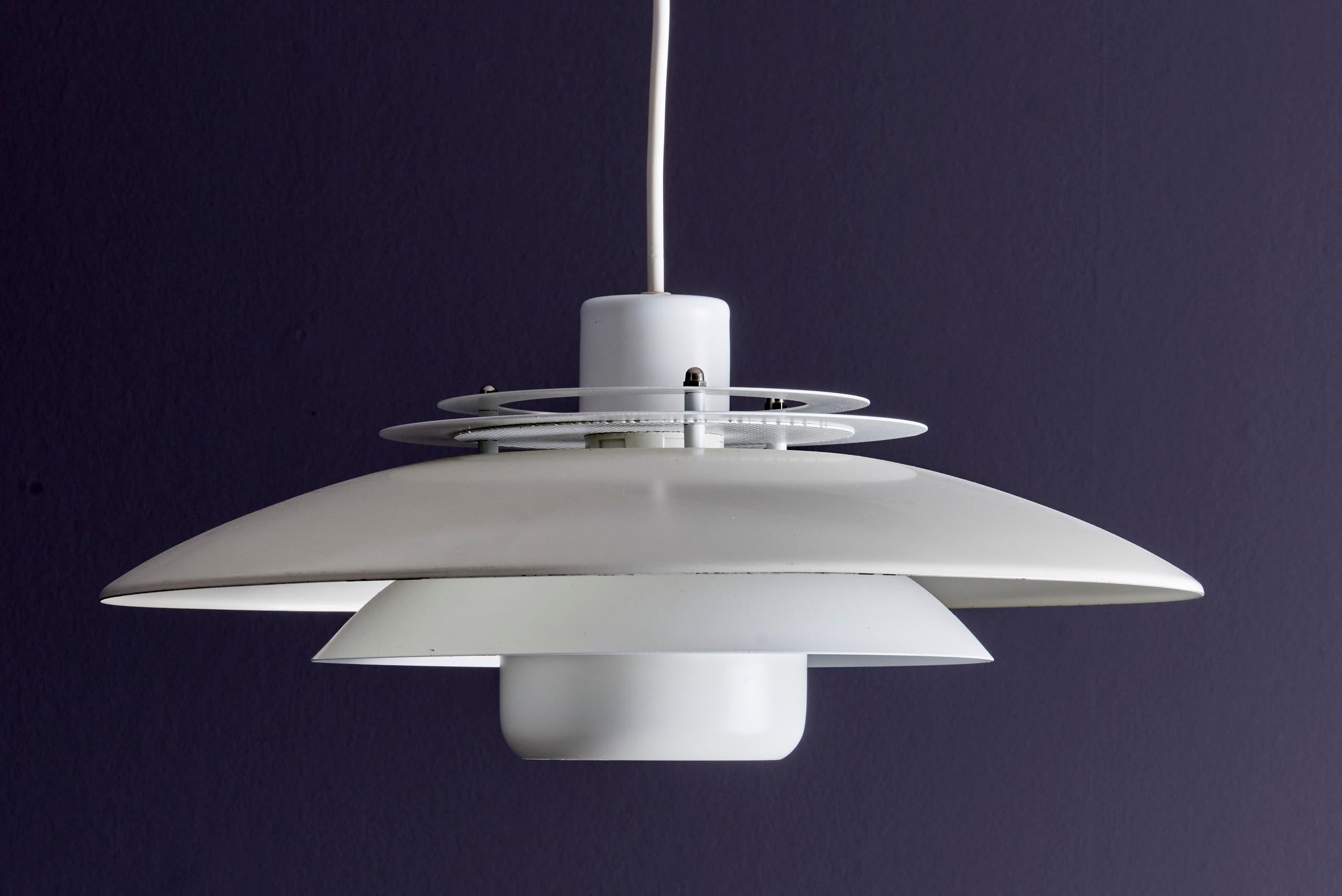 This pendant lamp is a mid‑century Scandinavian design classic, it features a signature multi‑disc construction in white lacquered metal — thick, layered concentric rings plus a top diffuser — which provides soft, indirect, glare‑free illumination.