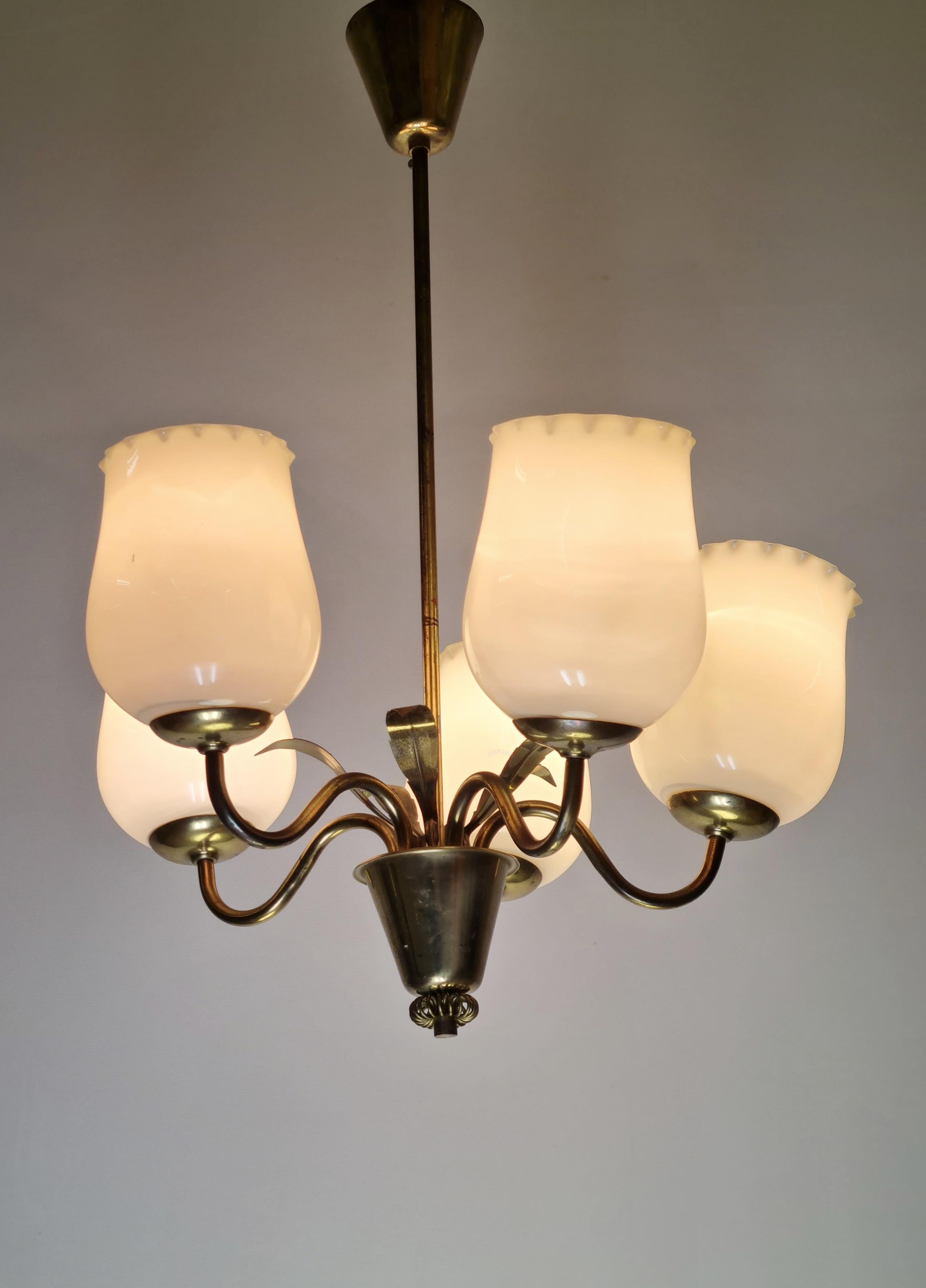 Pendente da soffitto finlandese Mid-Century Modern di Sievä degli anni '50. La lampada è caratterizzata da un corpo in ottone con decorazioni in foglie di ottone. Il modello è dotato di cinque lampadine dietro a paralumi soffiati in bocca. Il design