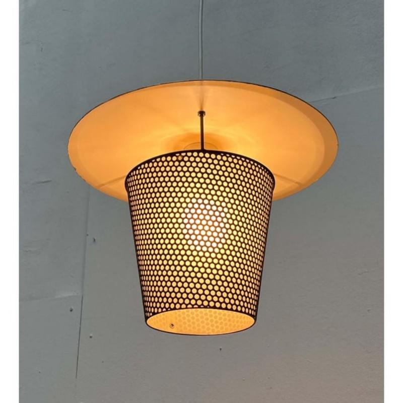 Lampe suspendue du milieu du siècle dernier, datant des années 1950.

Le détail frappant de ce luminaire en métal est sa perforation. La lampe se termine en haut par un abat-jour qui sert de réflecteur. Le panier diffuseur est monté sur trois barres