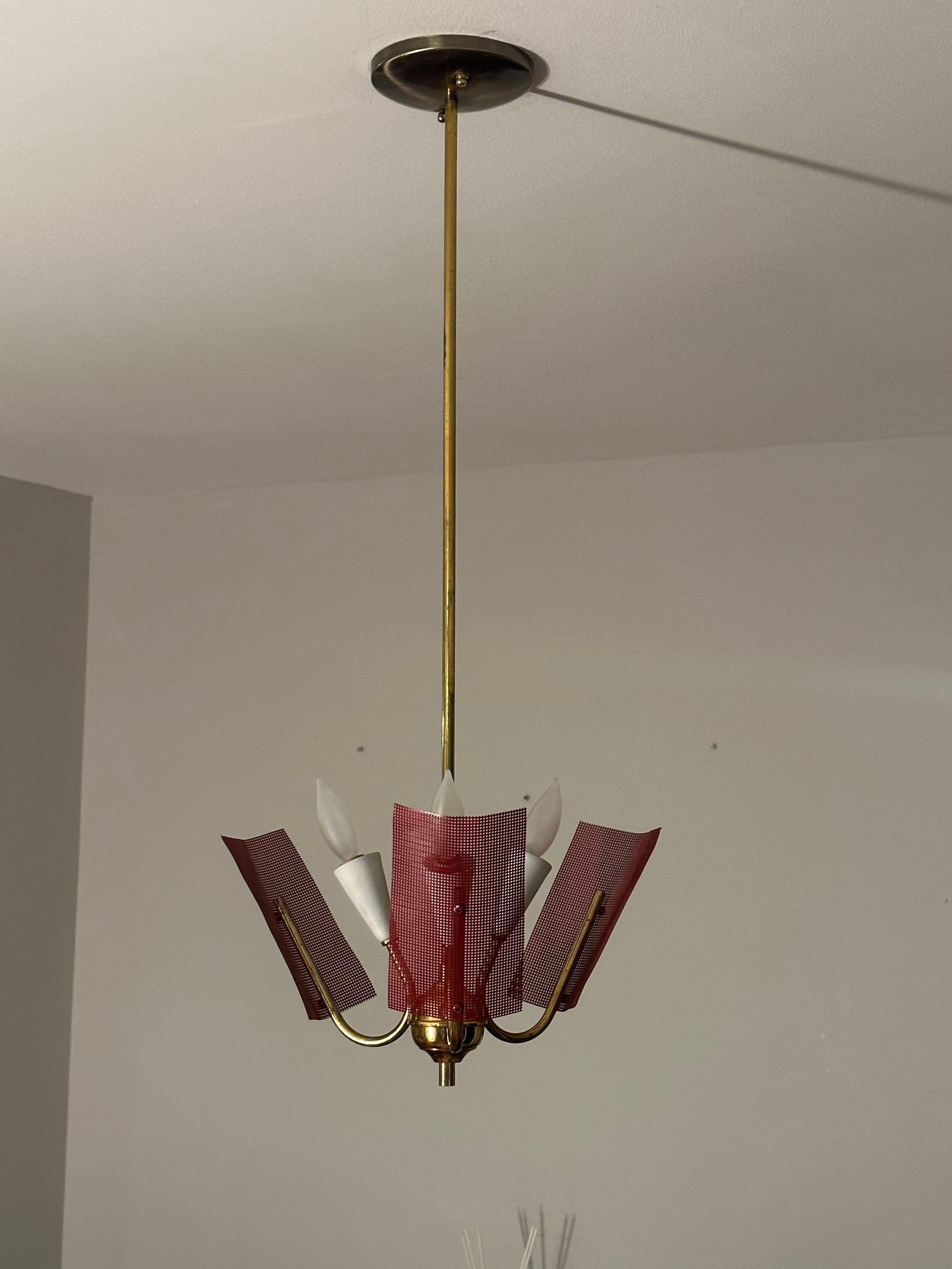A wonderful mid century modern chandelier circa 1950s and likely produced in Italy or Austria. Great perforated red metal screens, and nice movement in the arms. 

Would work well along side works from Angelo Lelii, Gino Sarfatti, JT Kalmar, etc 