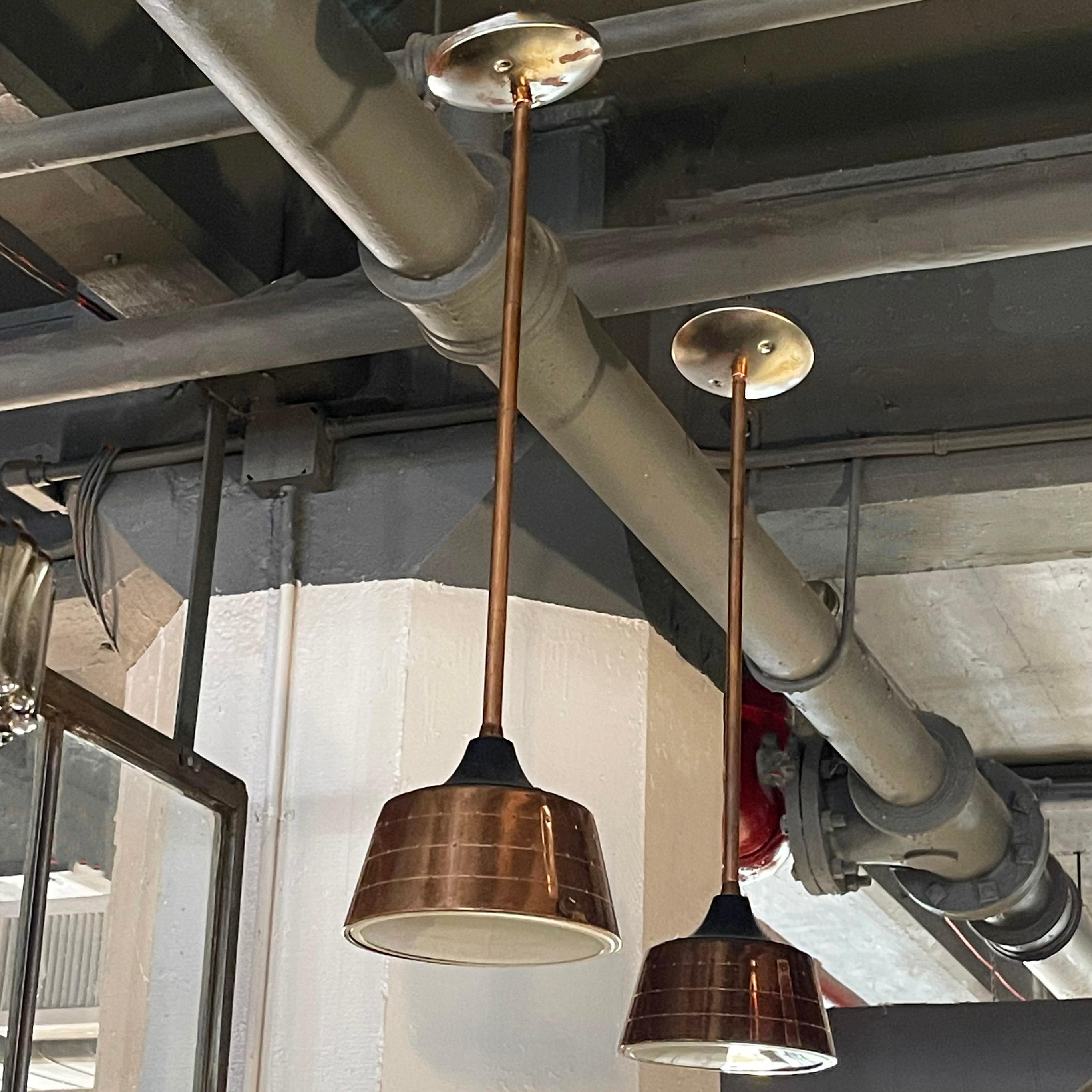 Pair of Mid-Century Modern, pendant lights by Lightolier feature 5 inch height, perforated, spun aluminum shades on poles with glass diffusers. Canopies shown are included. The pendants are newly wired to accept up to a 75 watt, medium socket bulb