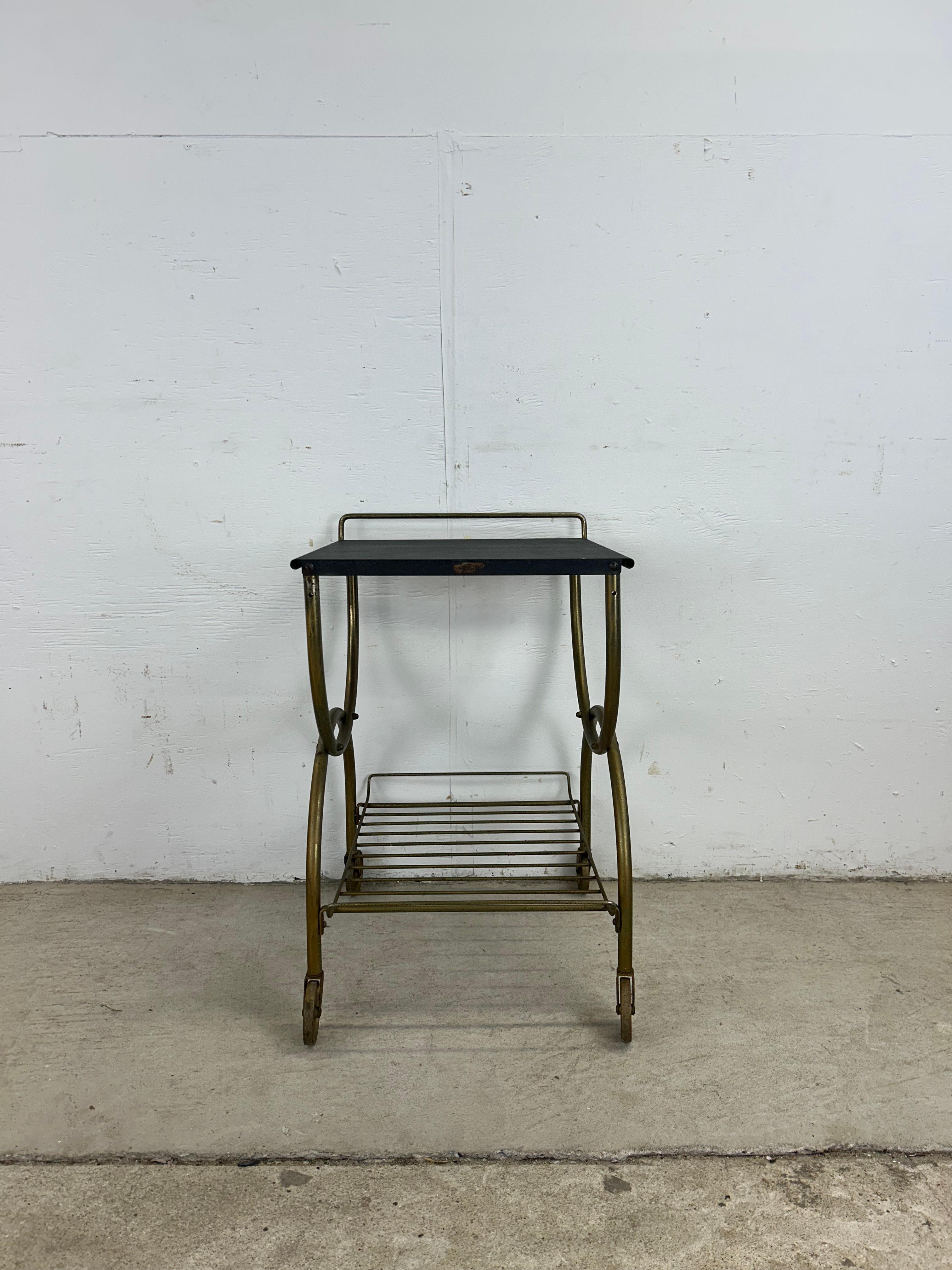 Dieser moderne Barwagen aus der Mitte des Jahrhunderts zeichnet sich durch eine Metallkonstruktion, ein zierliches Design, eine schwarz lackierte Platte, einen messingfarbenen Sockel mit Drahtkorb und messingfarbene Räder aus.

Abmessungen: 16.25b