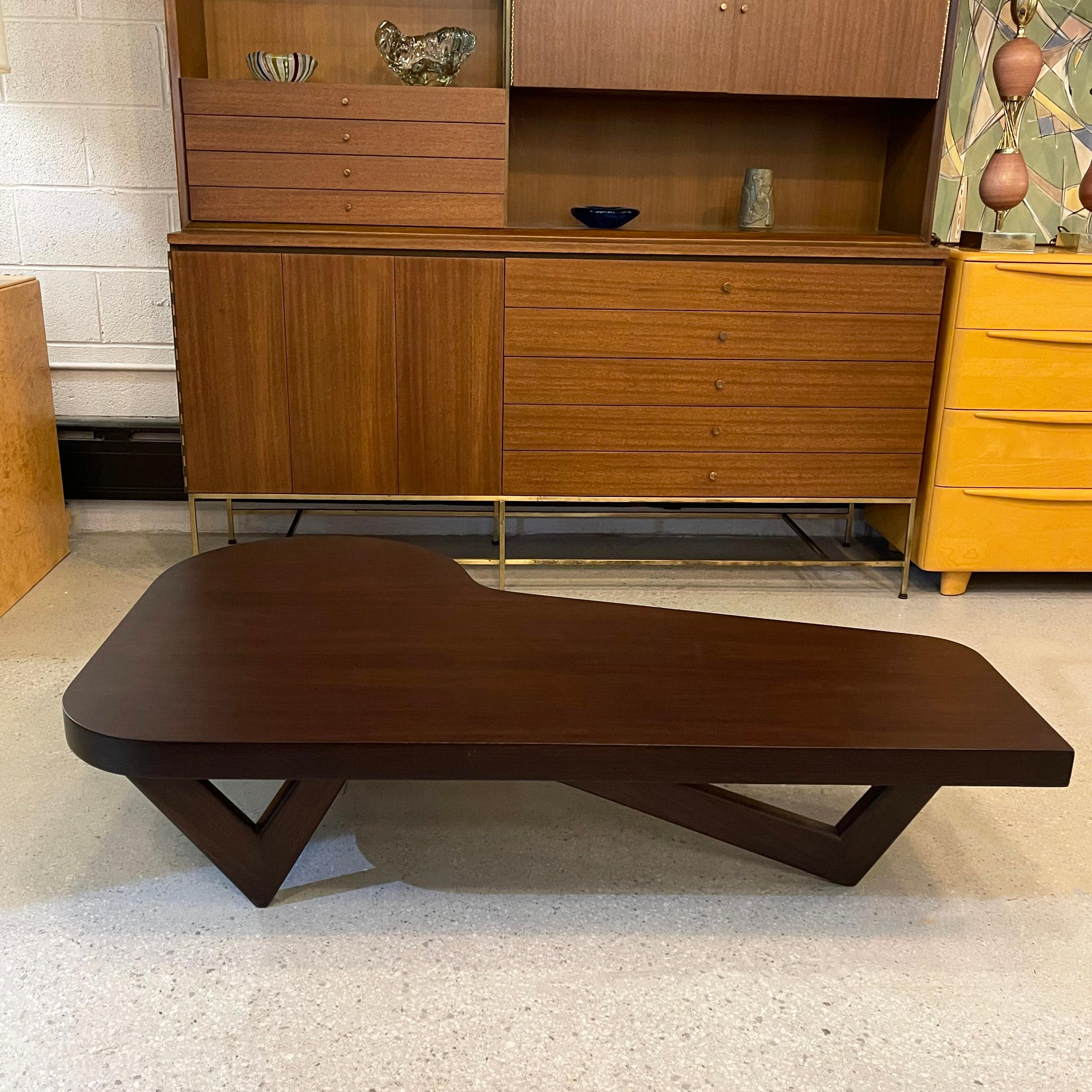 Outstanding, midcentury modern, low, mahogany coffee table fearures a thick biomorphic, piano-shaped top with sculptural, v-shaped legs in the style of Paul Laszlo. The table tapers from the center at 23.5 inches deep to 16 inches deep at it's most