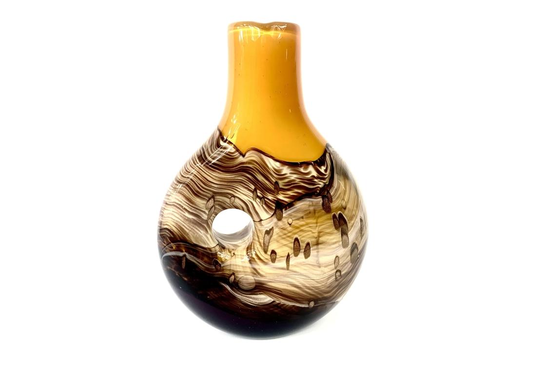Large pierced, hand-blown studio art glass vase, in a Mid-Century Modern  style with visual characteristics including swirl patterns, cased glass, gold inclusions, and a central hole design.

The vase features a unique, sculptural 