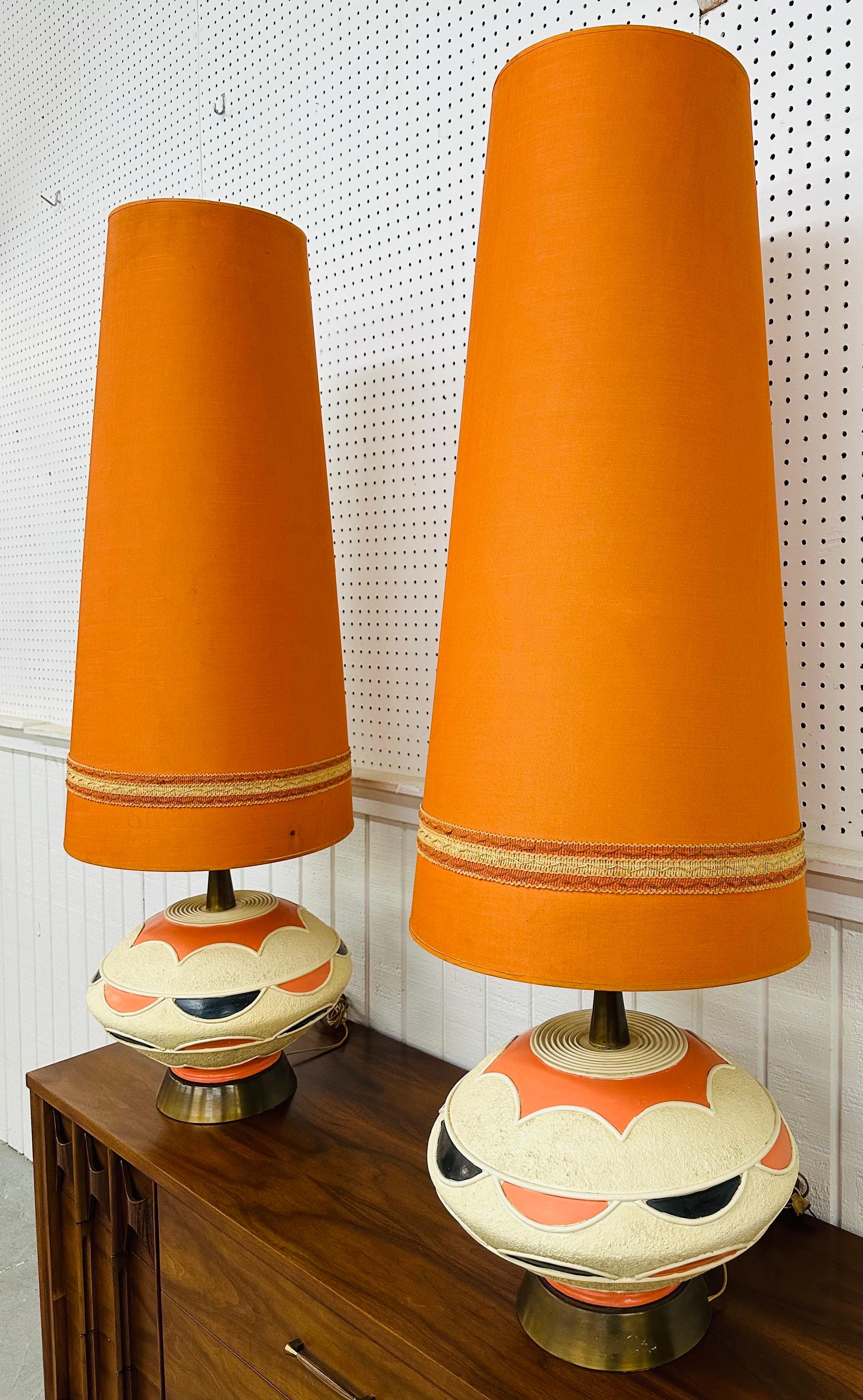 This listing is for a pair of Mid-Century Modern Pieri Tullio Large Ceramic Table Lamps. Featuring a UFO shaped design, ceramic body, brass base and neck, original large orange shades, and a beautiful black/orange painted body. This is an